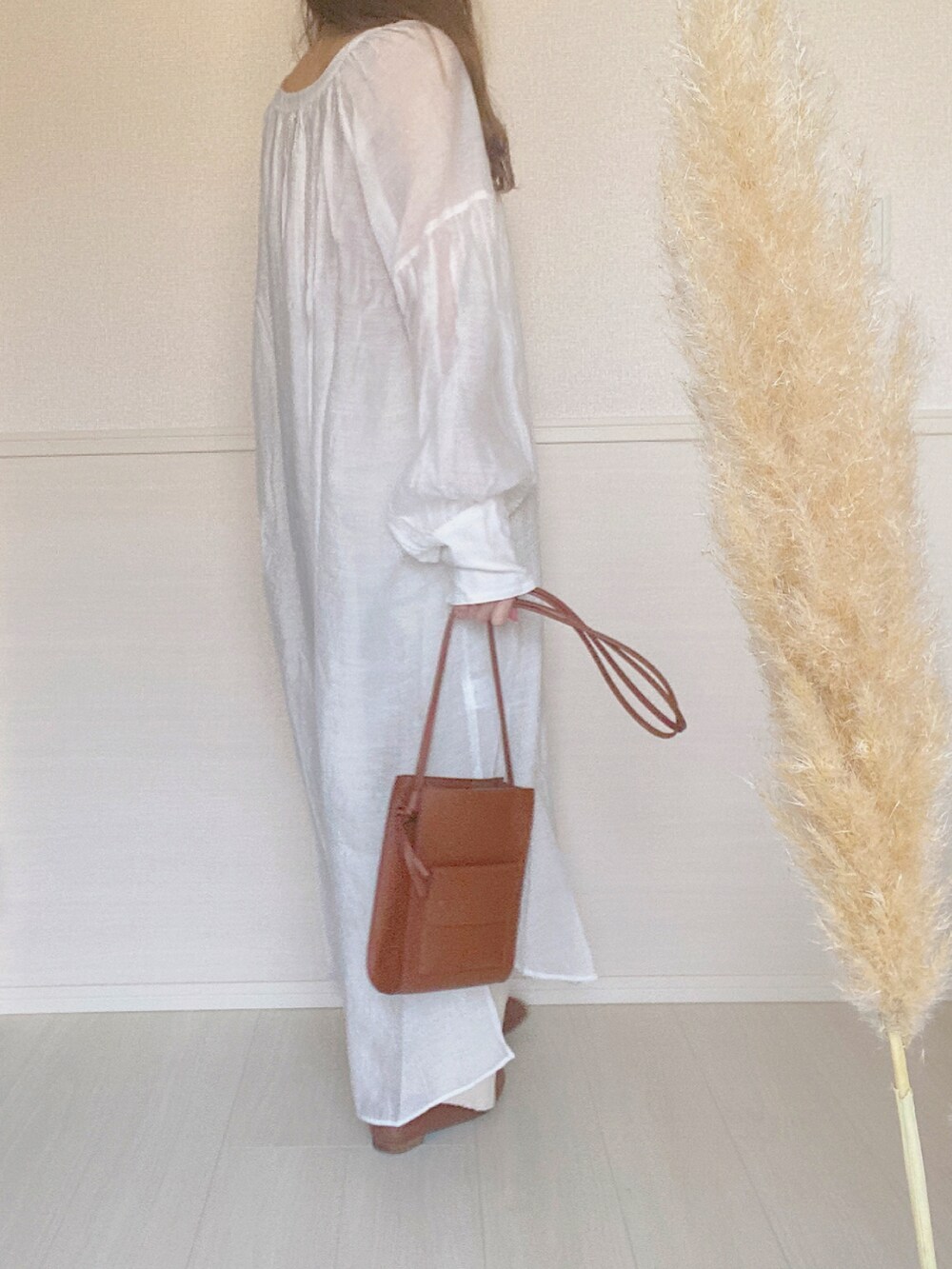 ホワイト系のシャツワンピース、ベージュ系のタンクトップ、ブラック系のパンプスを着用したレディースの春コーディネートの2枚目の写真