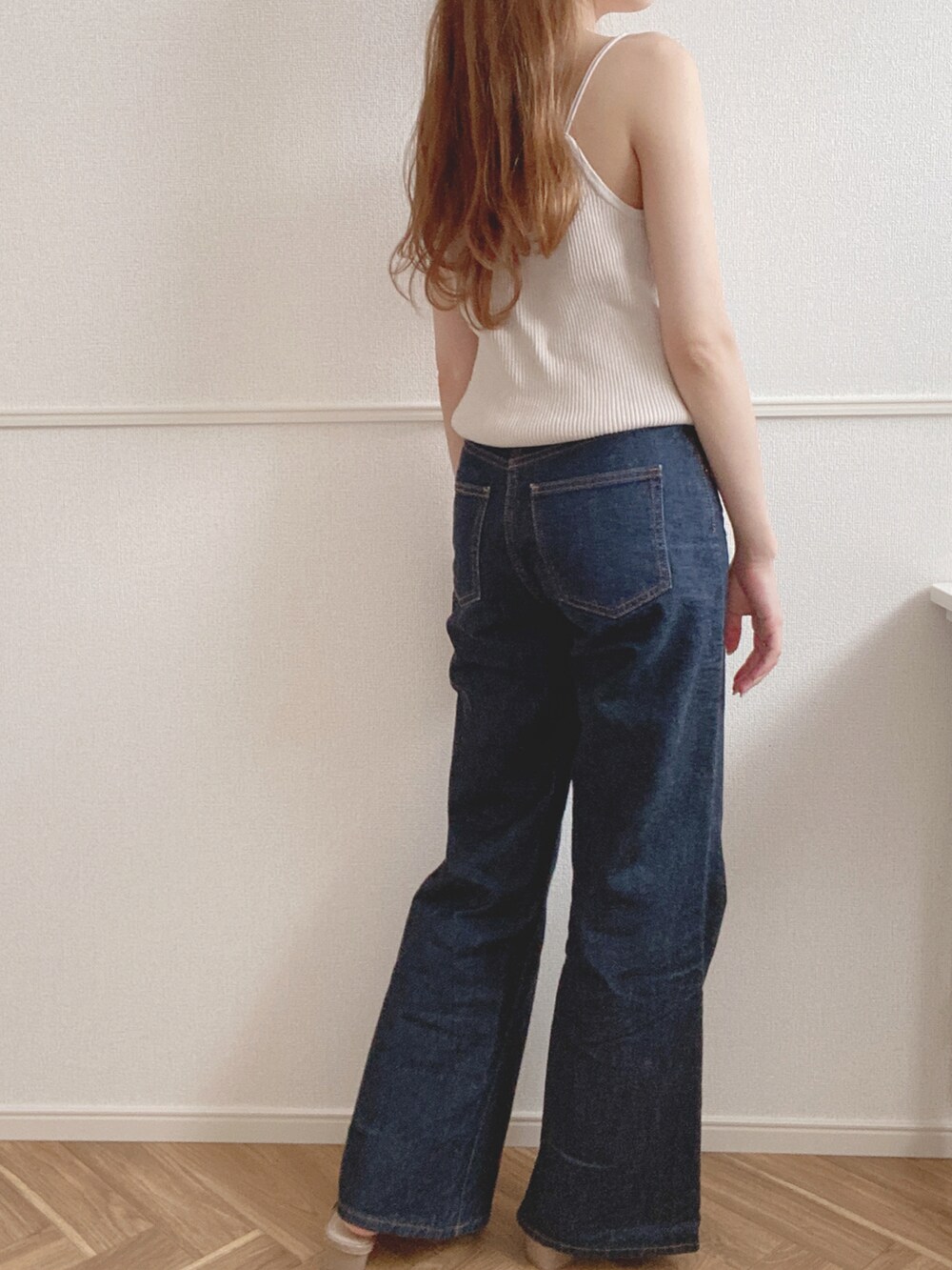 ホワイト系のキャミソール、ブルー系のデニムパンツ、ベージュ系のサンダルを着用したレディースの夏コーディネートの2枚目の写真