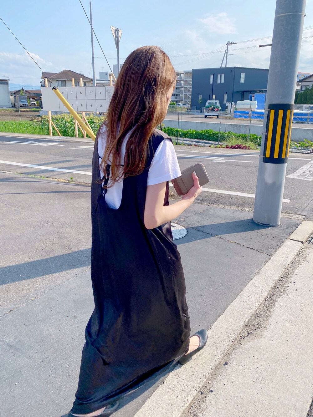 ブラック系のワンピース、ブラック系のパンプス、ホワイト系のTシャツ/カットソーを着用したレディースの夏コーディネートの2枚目の写真