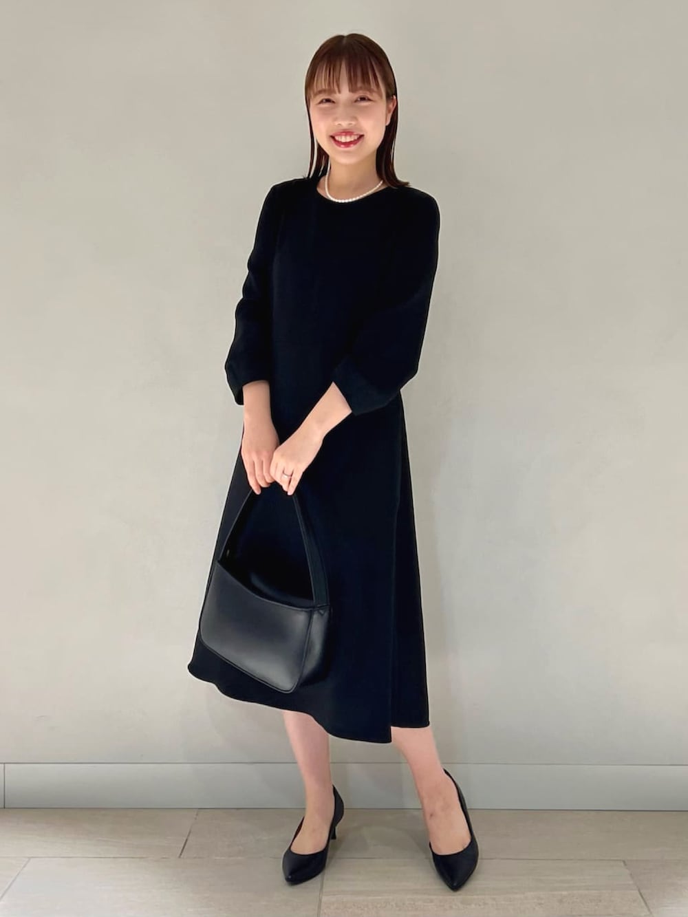 ブルー系のノーカラージャケット、ブルー系のワンピース、ブラック系のハンドバッグを着用したレディースの冬コーディネートの3枚目の写真