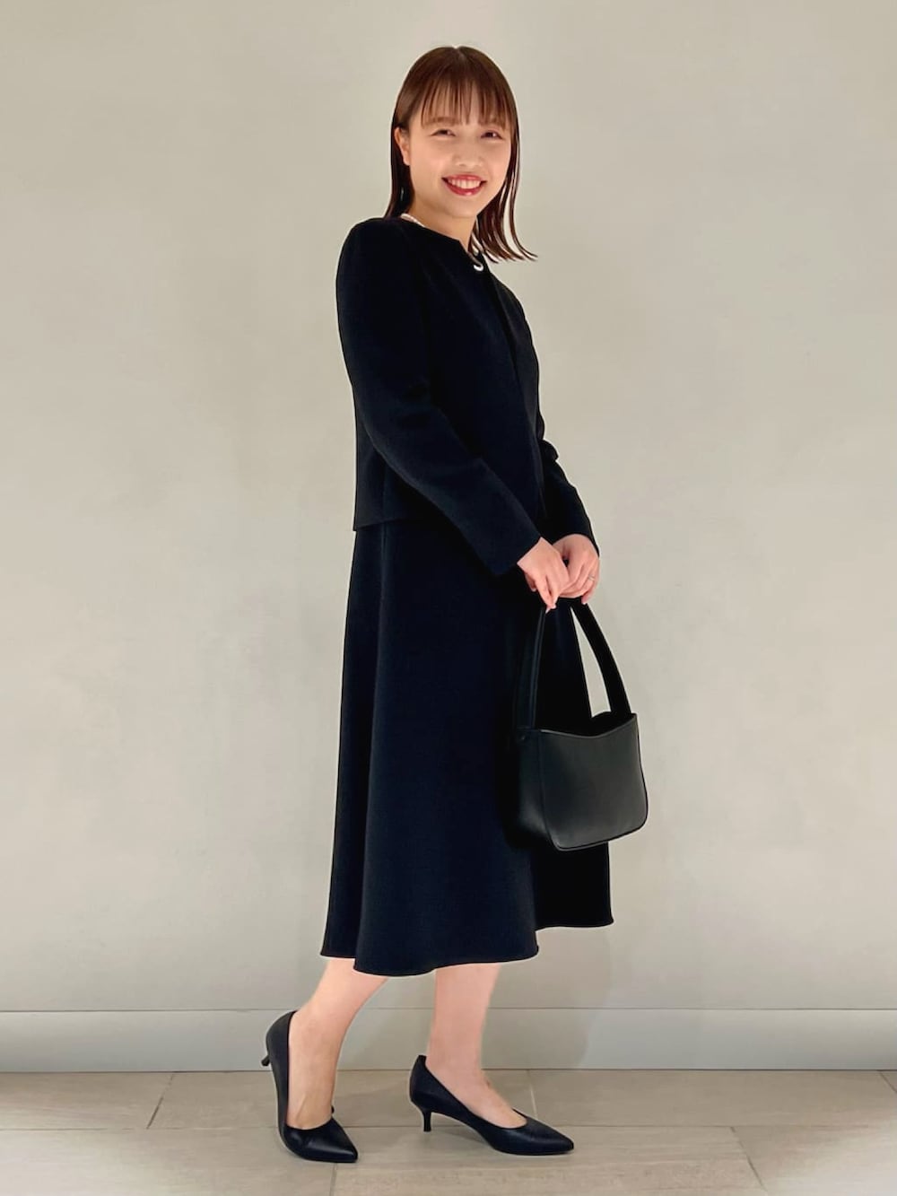 ブルー系のノーカラージャケット、ブルー系のワンピース、ブラック系のハンドバッグを着用したレディースの冬コーディネートの5枚目の写真