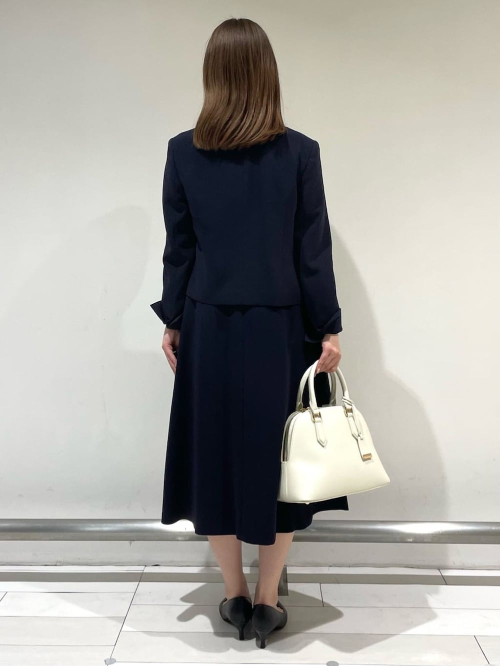 ブルー系のノーカラージャケット、ブルー系のワンピース、ベージュ系のハンドバッグを着用したレディースの冬コーディネートの4枚目の写真