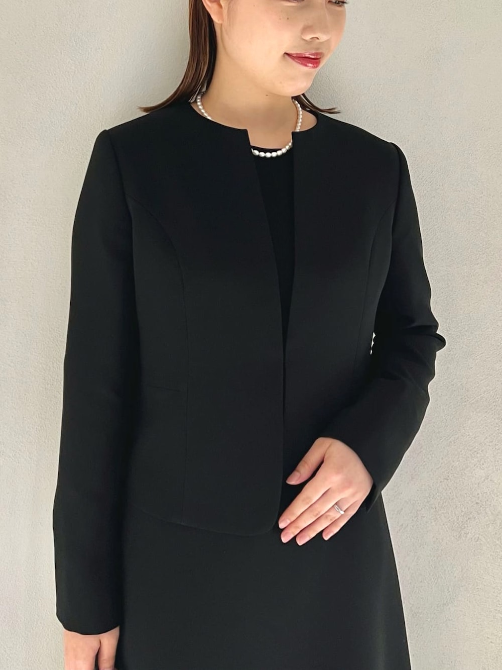 ブルー系のノーカラージャケット、ブルー系のワンピース、ブラック系のハンドバッグを着用したレディースの冬コーディネートの4枚目の写真