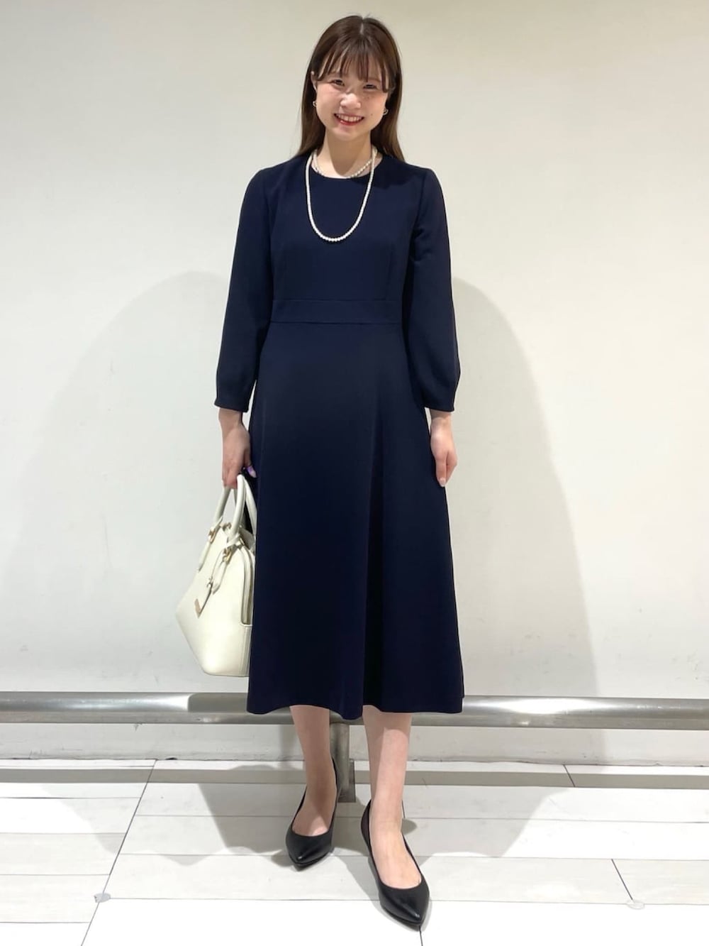 ブルー系のノーカラージャケット、ブルー系のワンピース、ベージュ系のハンドバッグを着用したレディースの冬コーディネートの2枚目の写真