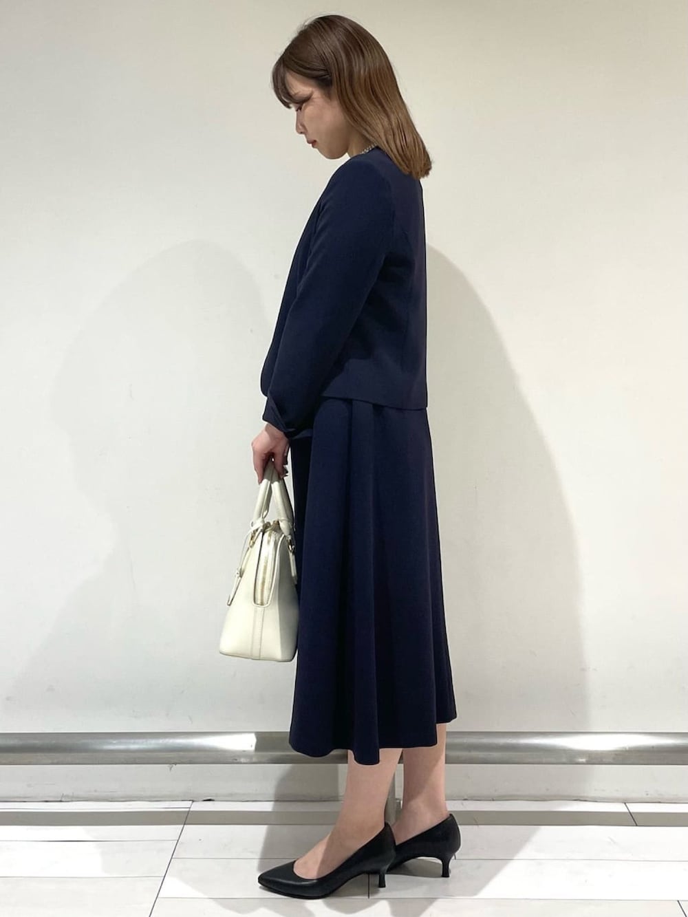 ブルー系のノーカラージャケット、ブルー系のワンピース、ベージュ系のハンドバッグを着用したレディースの冬コーディネートの3枚目の写真