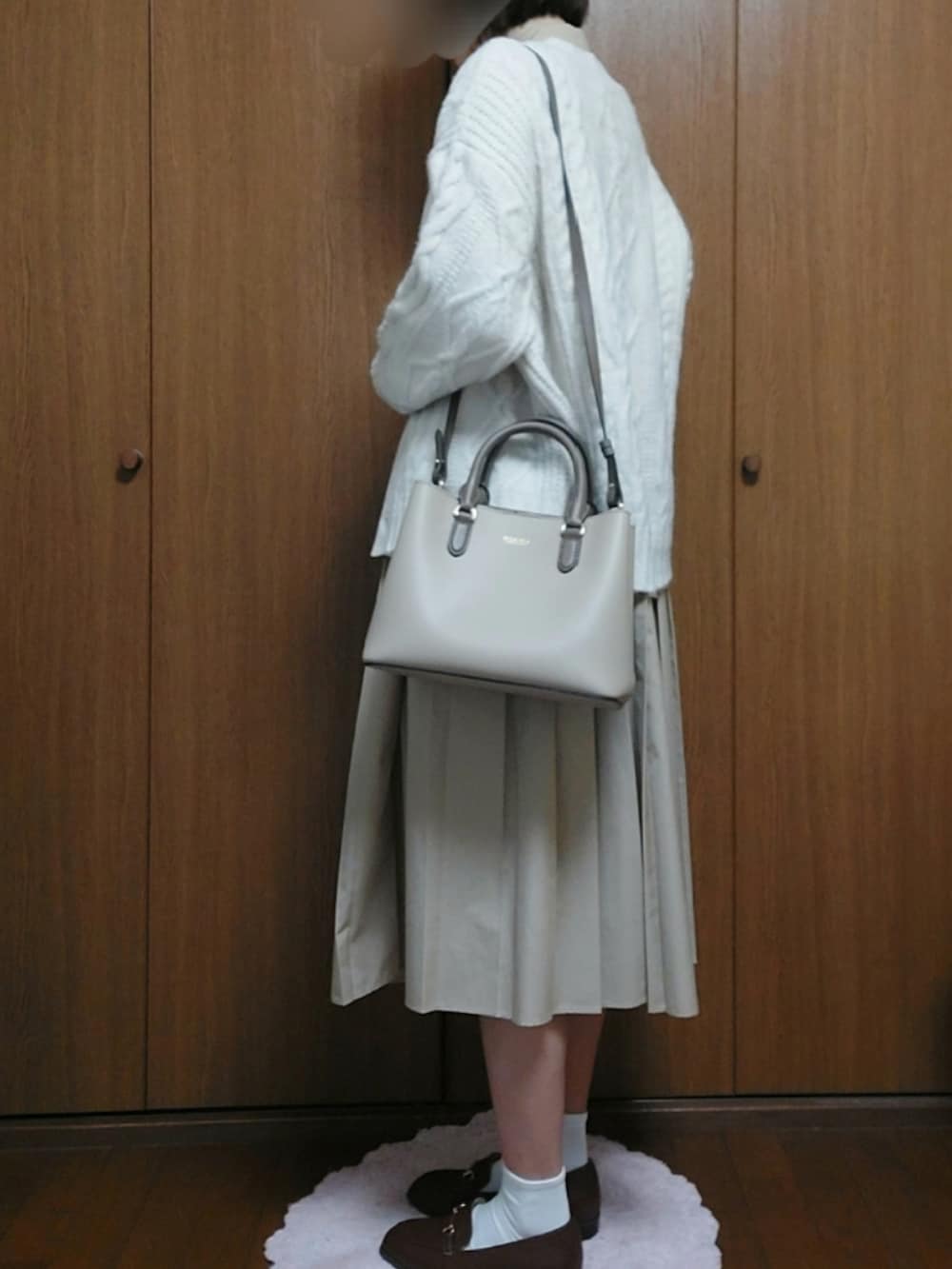 ベージュ系のショルダーバッグ、ブラウン系のローファー、ホワイト系のカーディガン/ボレロを着用したレディースの秋コーディネートの2枚目の写真