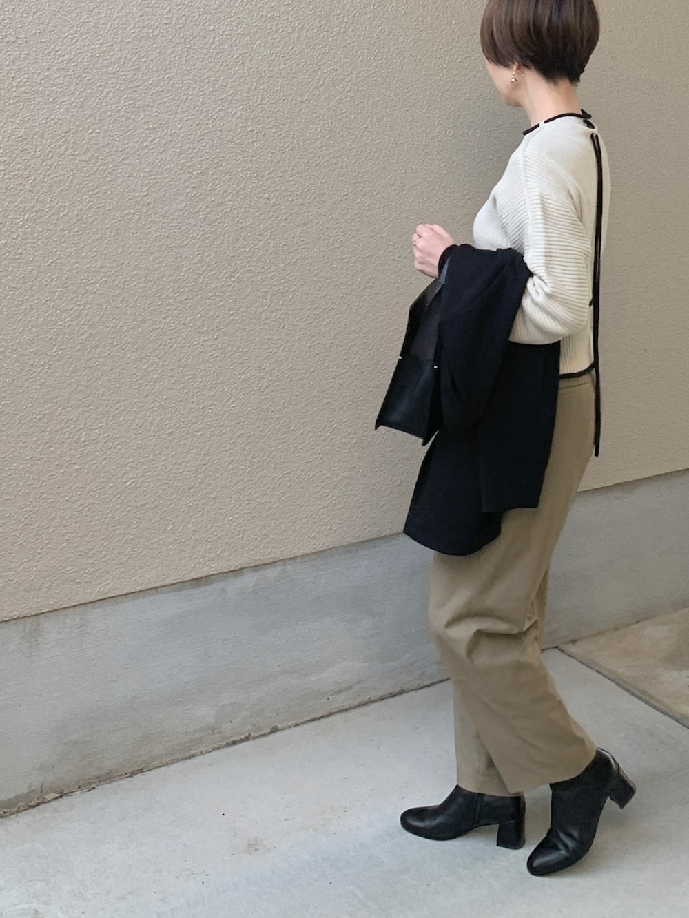 ホワイト系のニット/セーター、ブラック系のテーラードジャケット、ベージュ系のスラックスを着用したレディースの春コーディネートの3枚目の写真