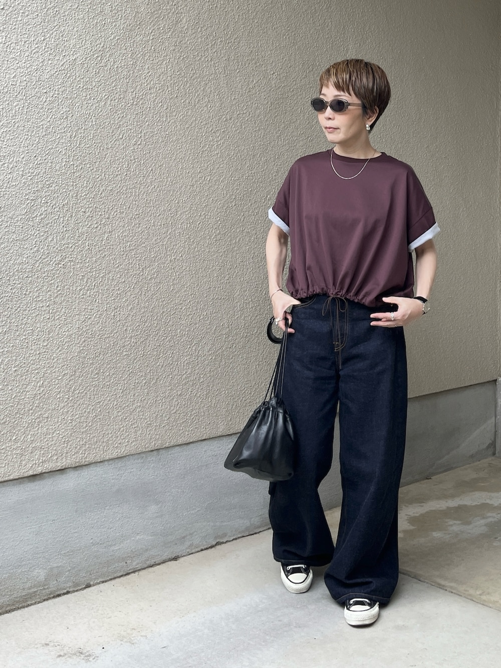 レッド系のTシャツ/カットソー、ブルー系のデニムパンツ、グレー系のサングラスを着用したレディースの春コーディネートの4枚目の写真