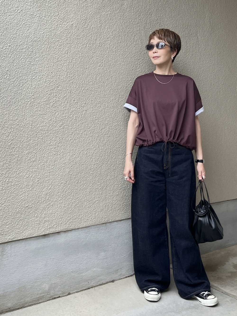 レッド系のTシャツ/カットソー、ブルー系のデニムパンツ、グレー系のサングラスを着用したレディースの春コーディネートの3枚目の写真