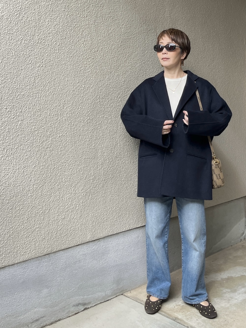 ブルー系のジャケット/アウター、ホワイト系のニット/セーター、ブルー系のデニムパンツを着用したレディースの春コーディネートの4枚目の写真