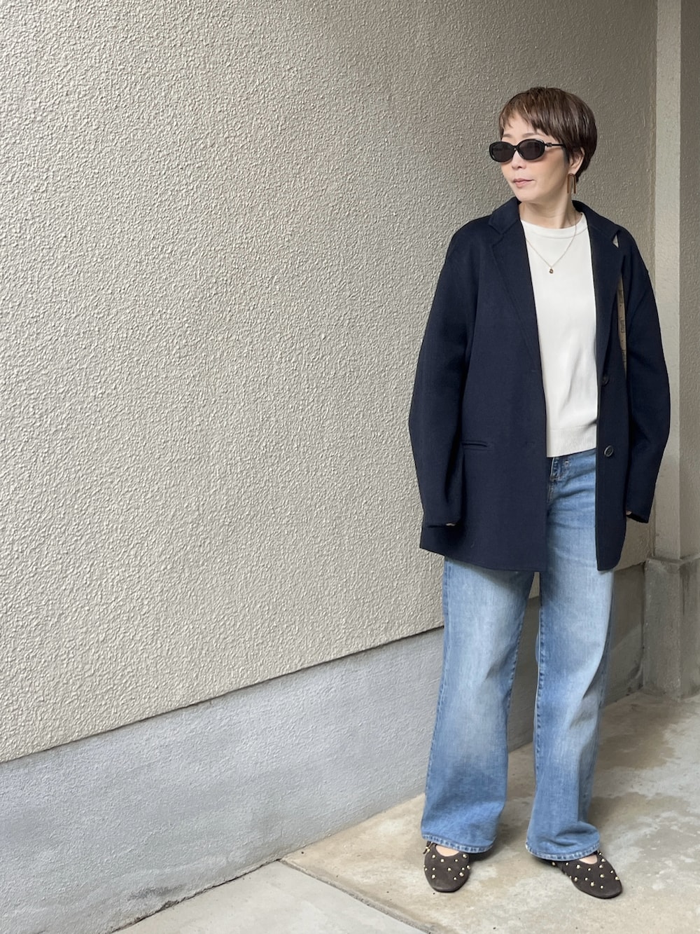 ブルー系のジャケット/アウター、ホワイト系のニット/セーター、ブルー系のデニムパンツを着用したレディースの春コーディネートの2枚目の写真