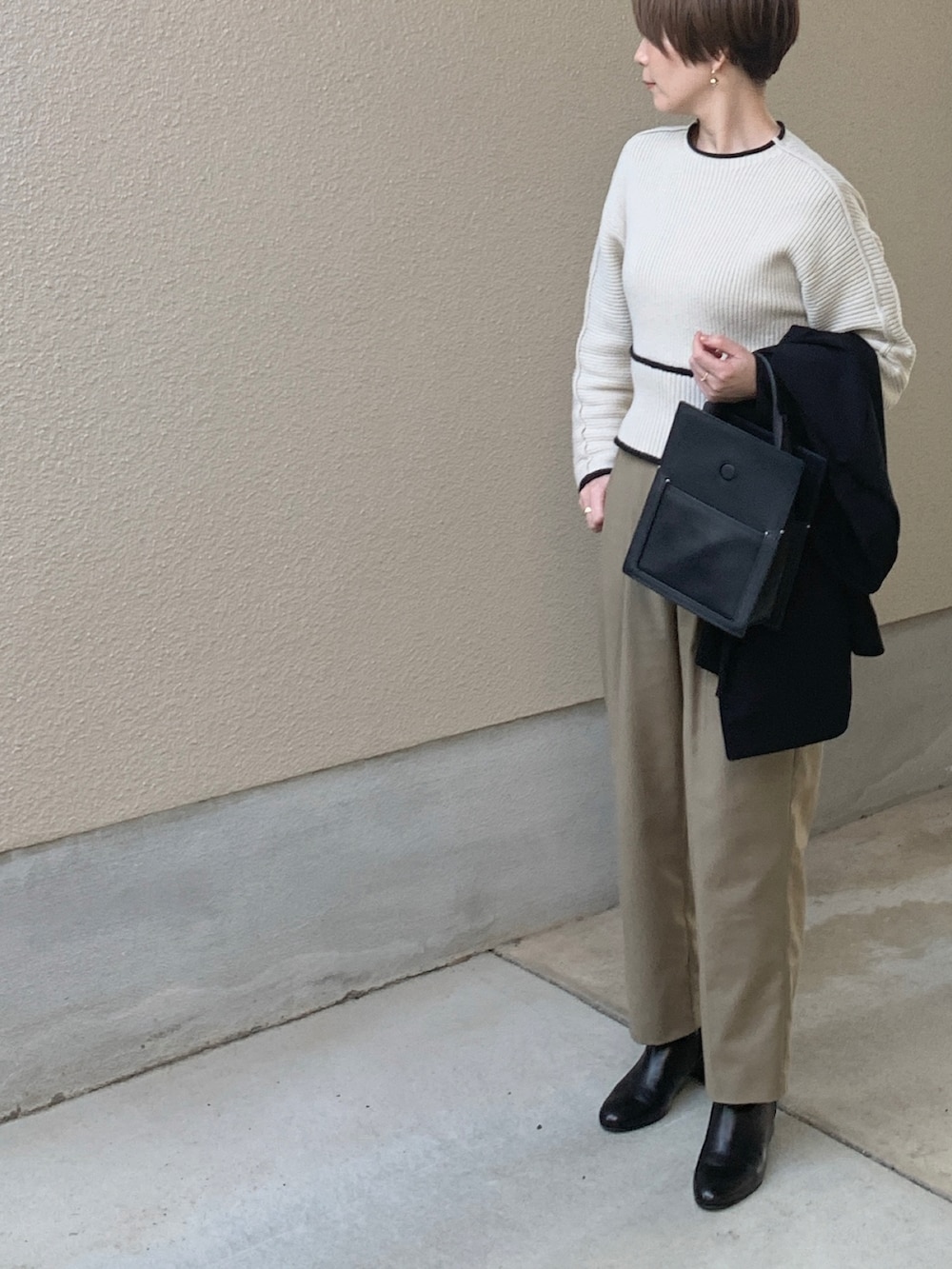 ホワイト系のニット/セーター、ブラック系のテーラードジャケット、ベージュ系のスラックスを着用したレディースの春コーディネートの4枚目の写真
