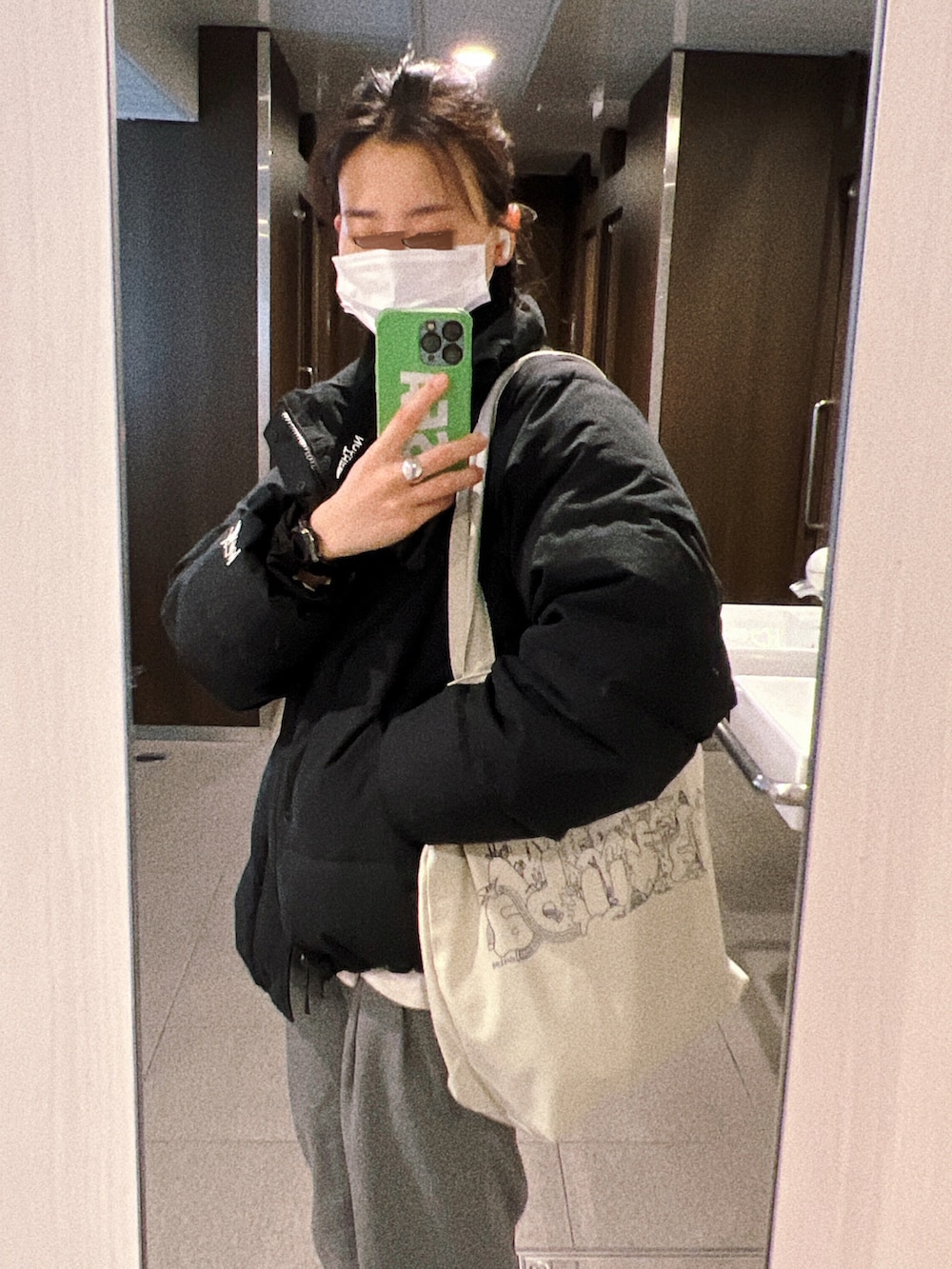 グレー系のその他パンツ、オレンジ系のニット/セーター、ブラック系のダウンジャケット/コートを着用したレディースの冬コーディネートの2枚目の写真