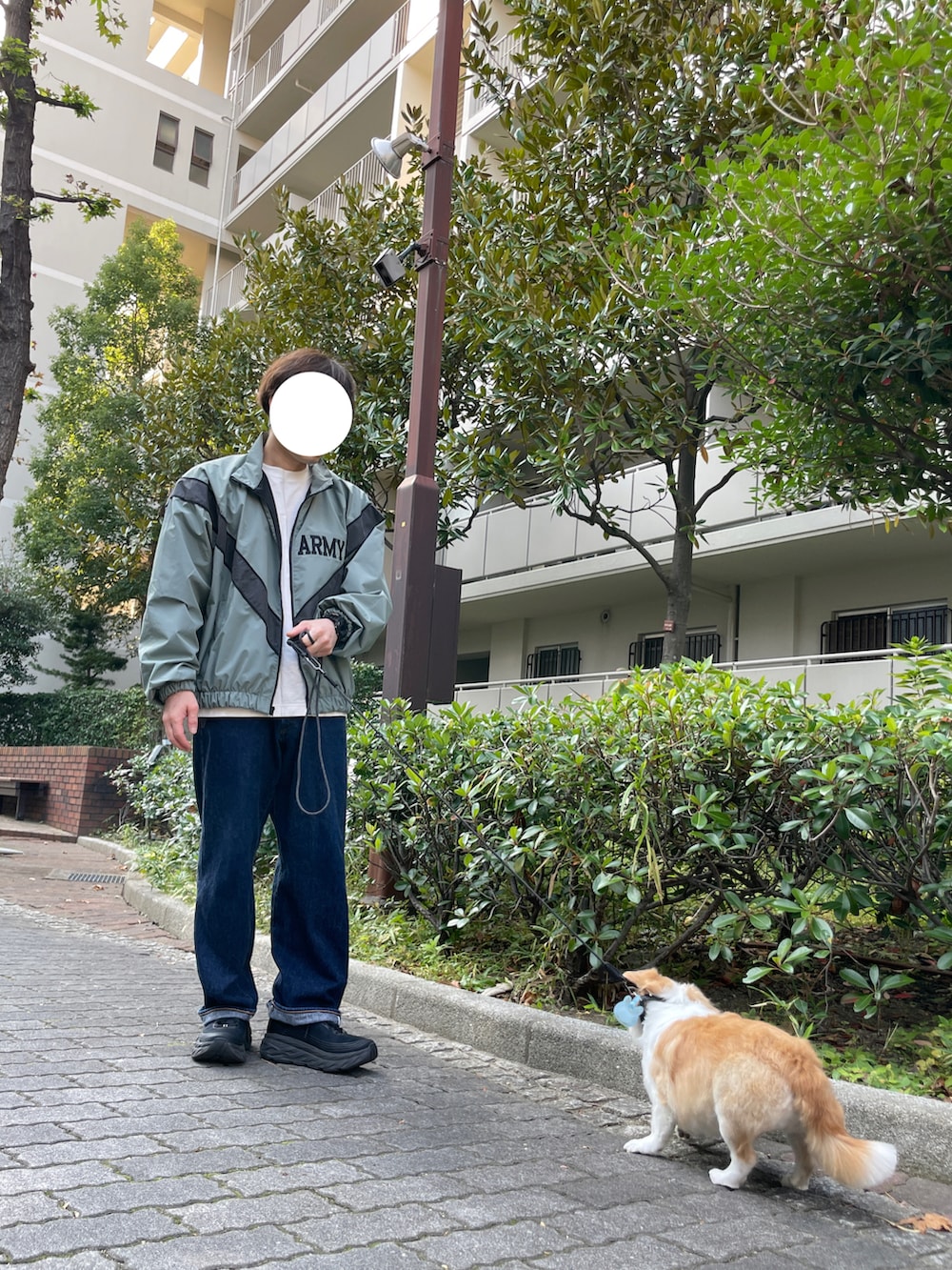 グレー系のナイロンジャケット、ブラック系のスニーカー、ブルー系のデニムパンツを着用したメンズの秋コーディネートの2枚目の写真