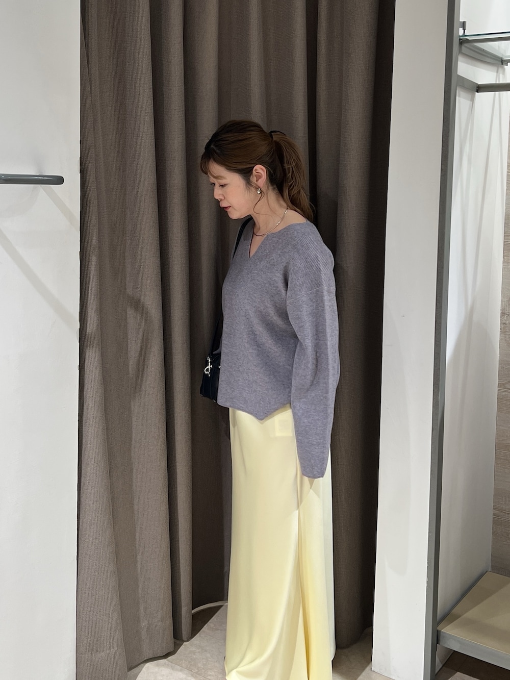 グレー系のニット/セーター、イエロー系のスカートを着用したレディースの春コーディネートの2枚目の写真
