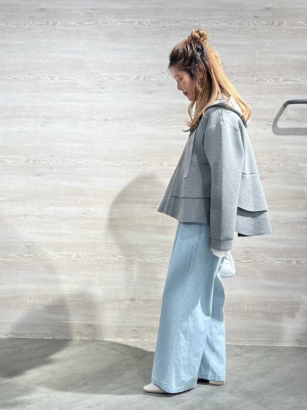 グレー系のパーカー、ブルー系のデニムパンツを着用したレディースの冬コーディネートの2枚目の写真