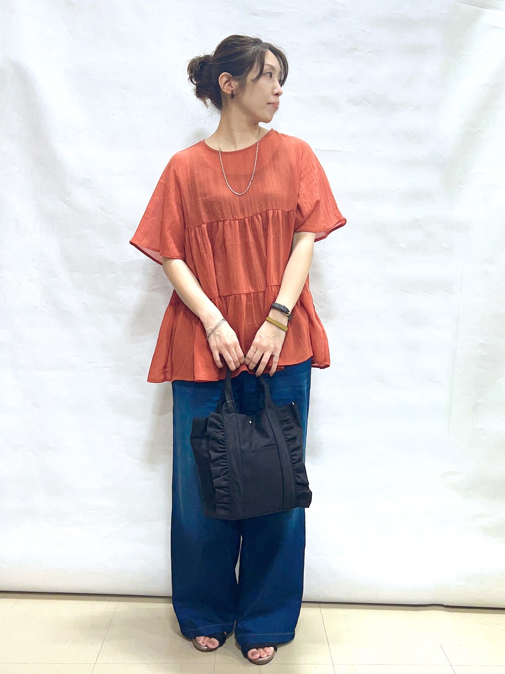 オレンジ系のシャツ/ブラウス、ブルー系のその他パンツ、ブラック系のサンダルを着用したレディースの夏コーディネートの4枚目の写真