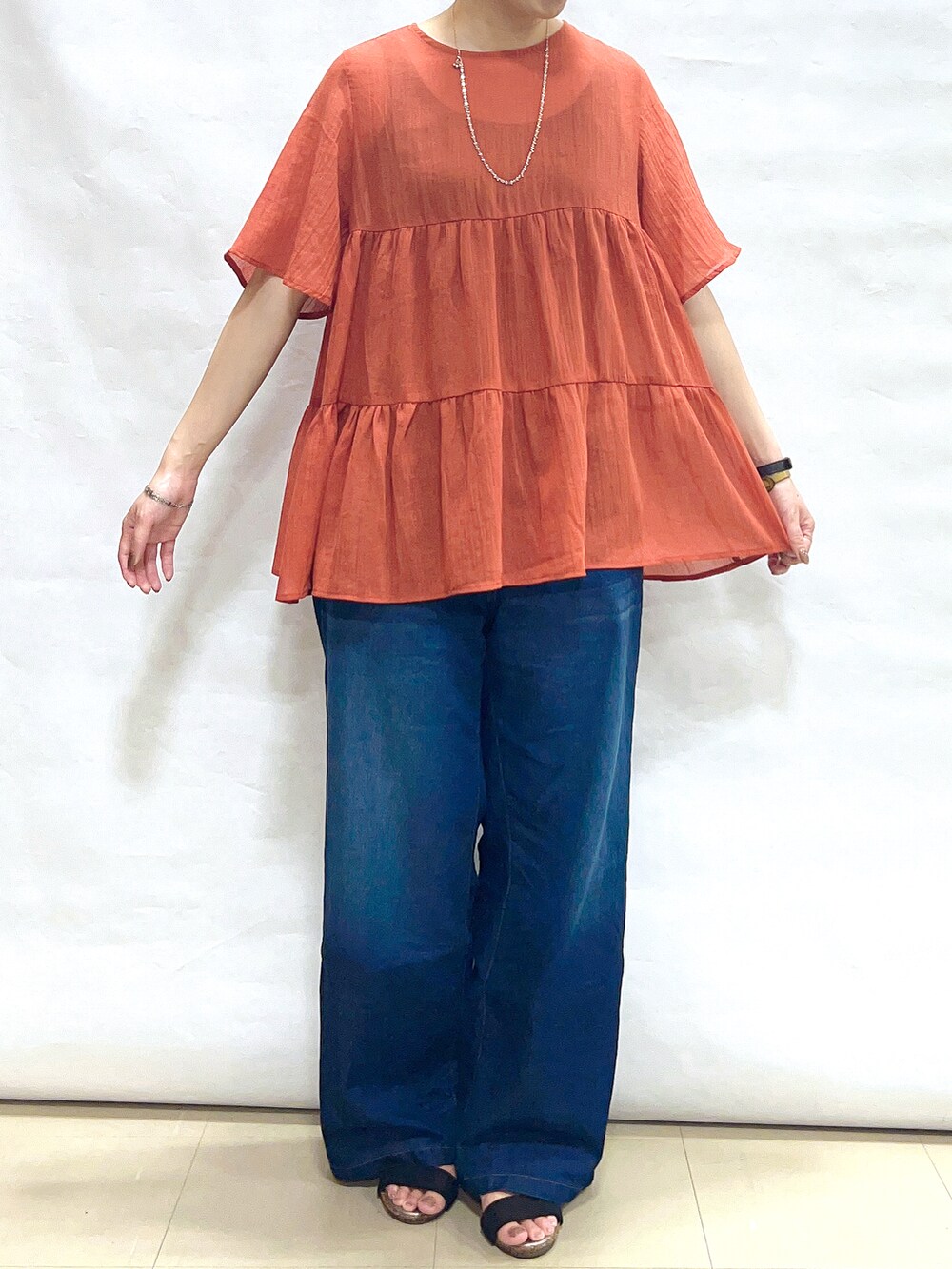 オレンジ系のシャツ/ブラウス、ブルー系のその他パンツ、ブラック系のサンダルを着用したレディースの夏コーディネートの5枚目の写真