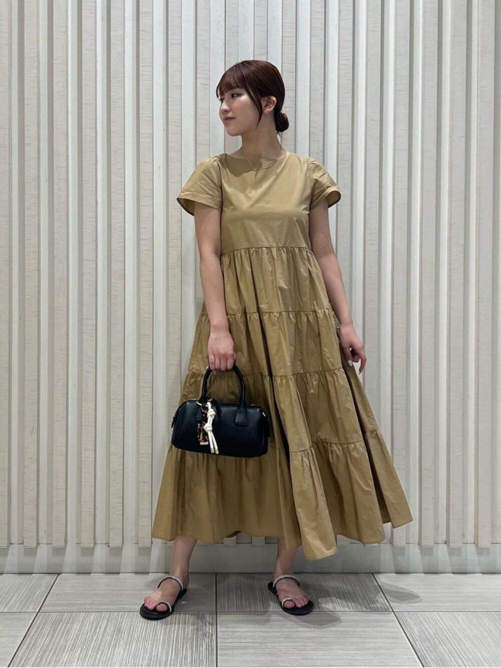 ベージュ系のワンピース、ブラウン系のサンダル、ブラウン系のボストンバッグを着用したレディースの夏コーディネートの2枚目の写真