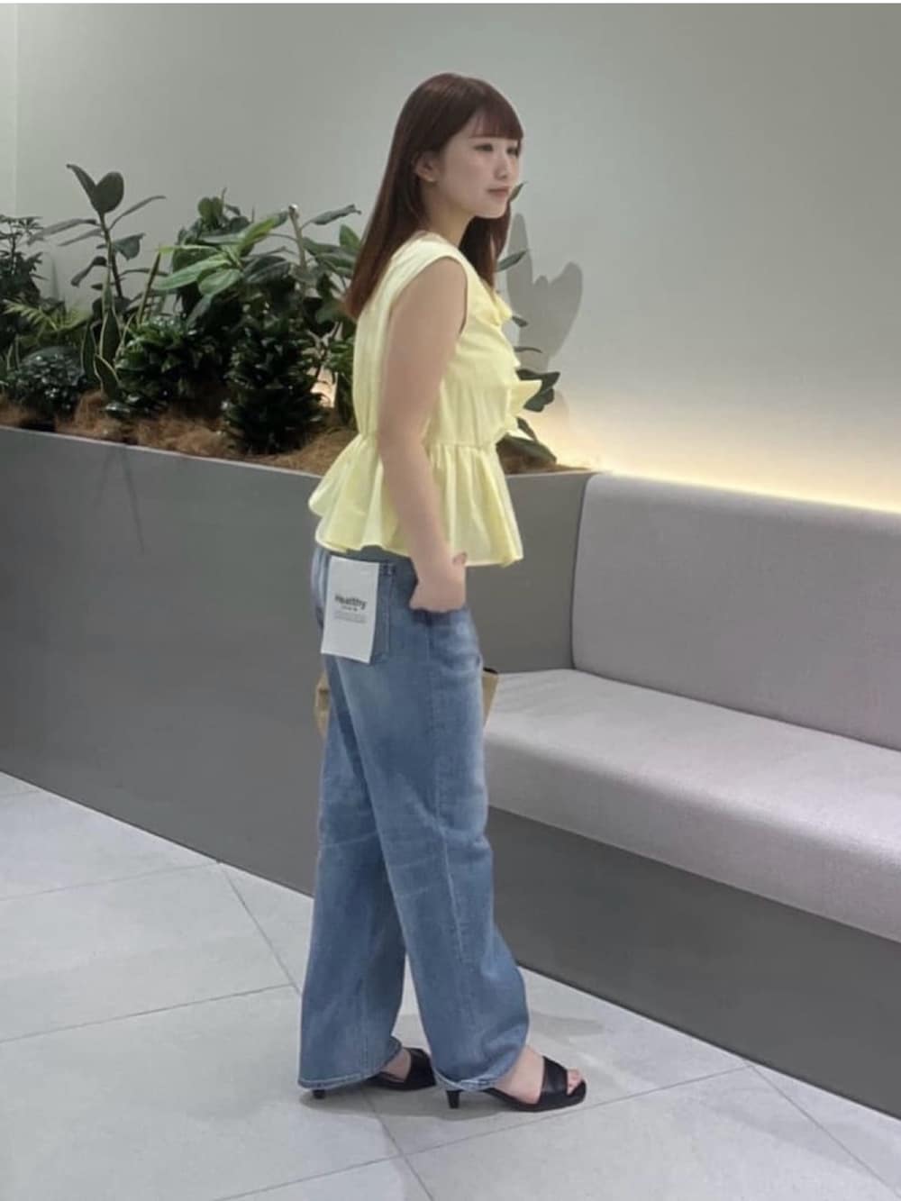 イエロー系のシャツ/ブラウス、ブルー系のデニムパンツ、ブラック系のサンダルを着用したレディースの夏コーディネートの3枚目の写真