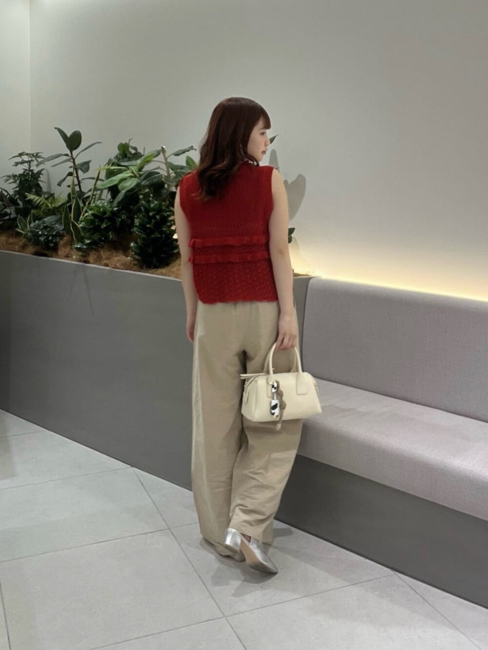レッド系のニット/セーター、ベージュ系のその他パンツ、ブラウン系のボストンバッグを着用したレディースの夏コーディネートの5枚目の写真