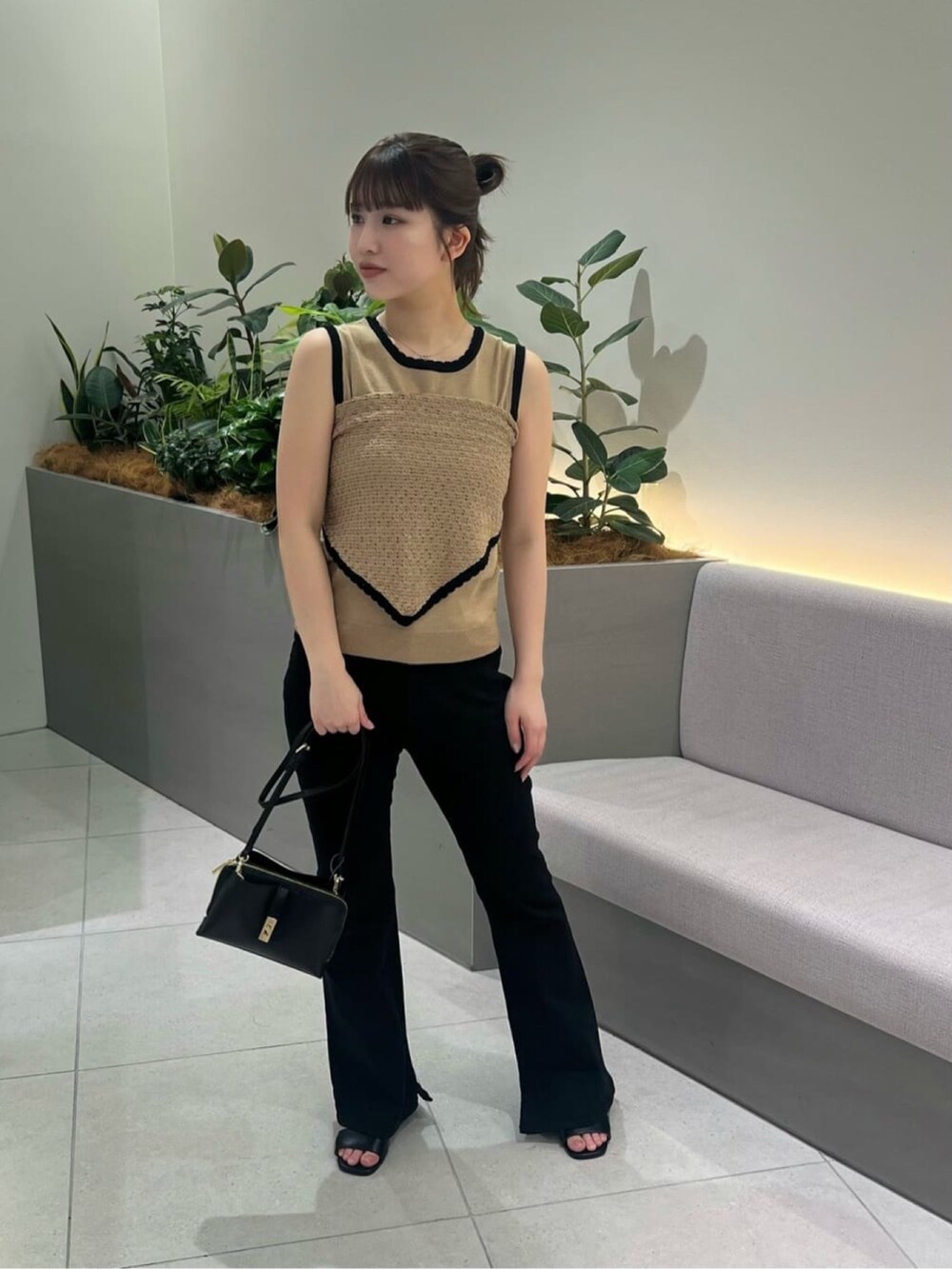 ベージュ系のニット/セーター、ブラック系のデニムパンツ、ブラック系のショルダーバッグを着用したレディースの夏コーディネートの3枚目の写真