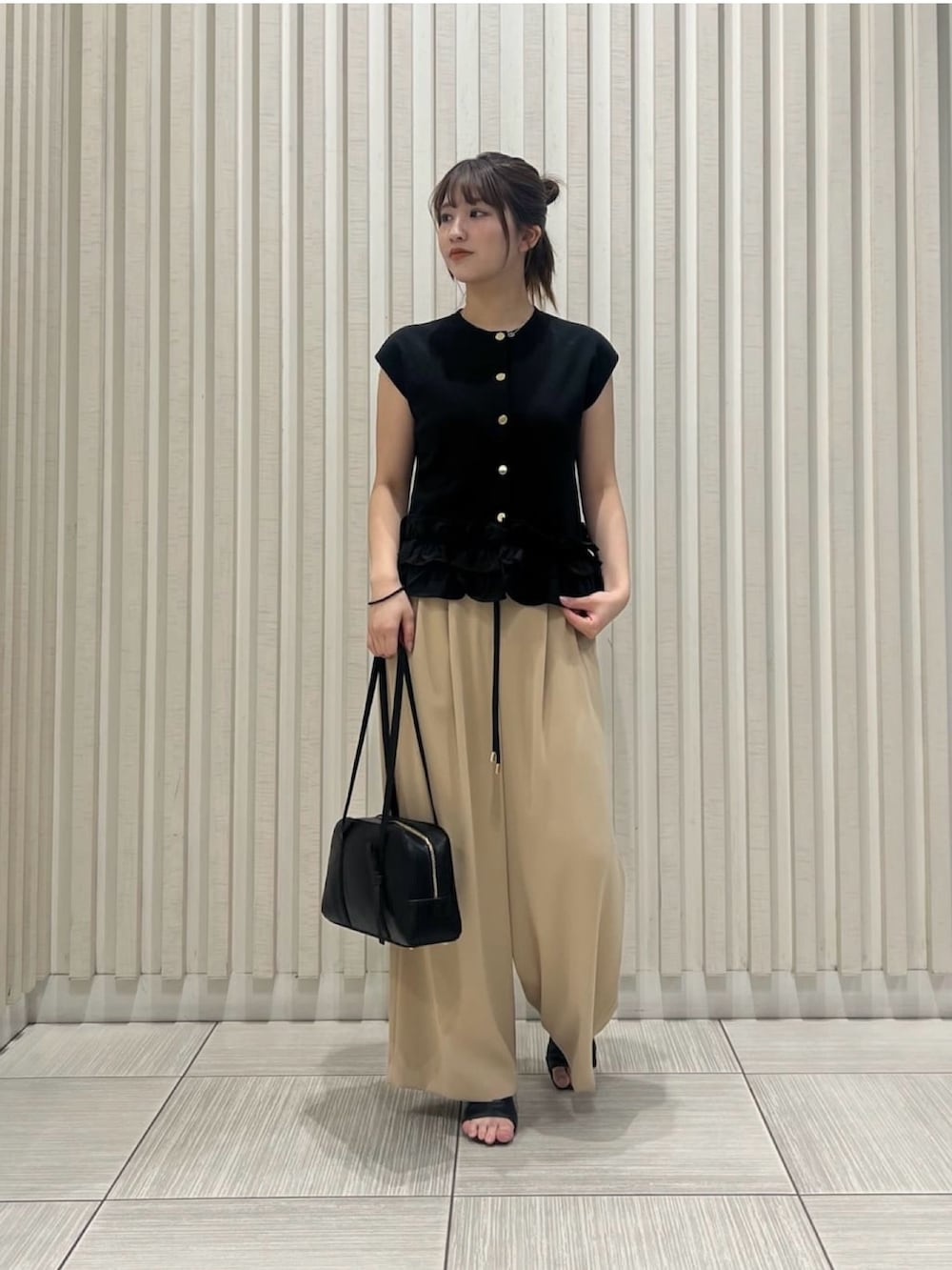 ブラック系のベスト、イエロー系のその他パンツ、ブラウン系のボストンバッグを着用したレディースの夏コーディネートの2枚目の写真