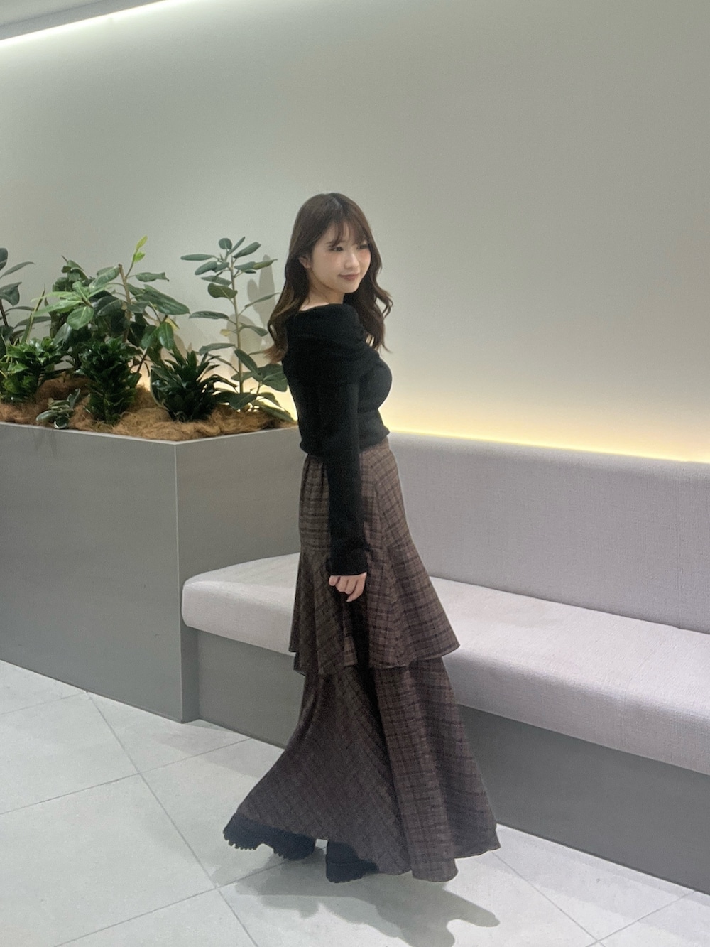 ブラック系のニット/セーター、ブラウン系のスカート、ブラック系のローファーを着用したレディースの秋コーディネートの6枚目の写真