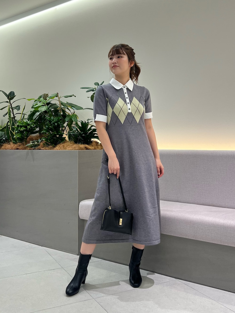 グレー系のワンピース、ブラック系のブーツ、ブラック系のショルダーバッグを着用したレディースの秋コーディネートの3枚目の写真