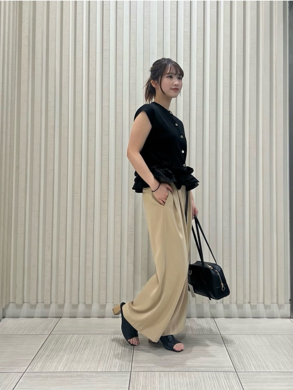 ブラック系のベスト、イエロー系のその他パンツ、ブラウン系のボストンバッグを着用したレディースの夏コーディネートの3枚目の写真