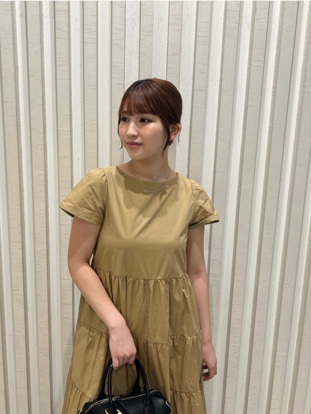 ベージュ系のワンピース、ブラウン系のサンダル、ブラウン系のボストンバッグを着用したレディースの夏コーディネートの6枚目の写真