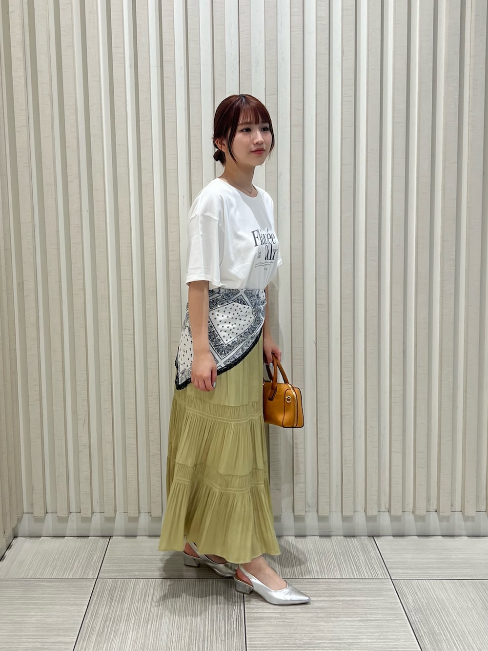 ホワイト系のTシャツ/カットソー、イエロー系のスカート、オレンジ系のボストンバッグを着用したレディースの夏コーディネートの4枚目の写真