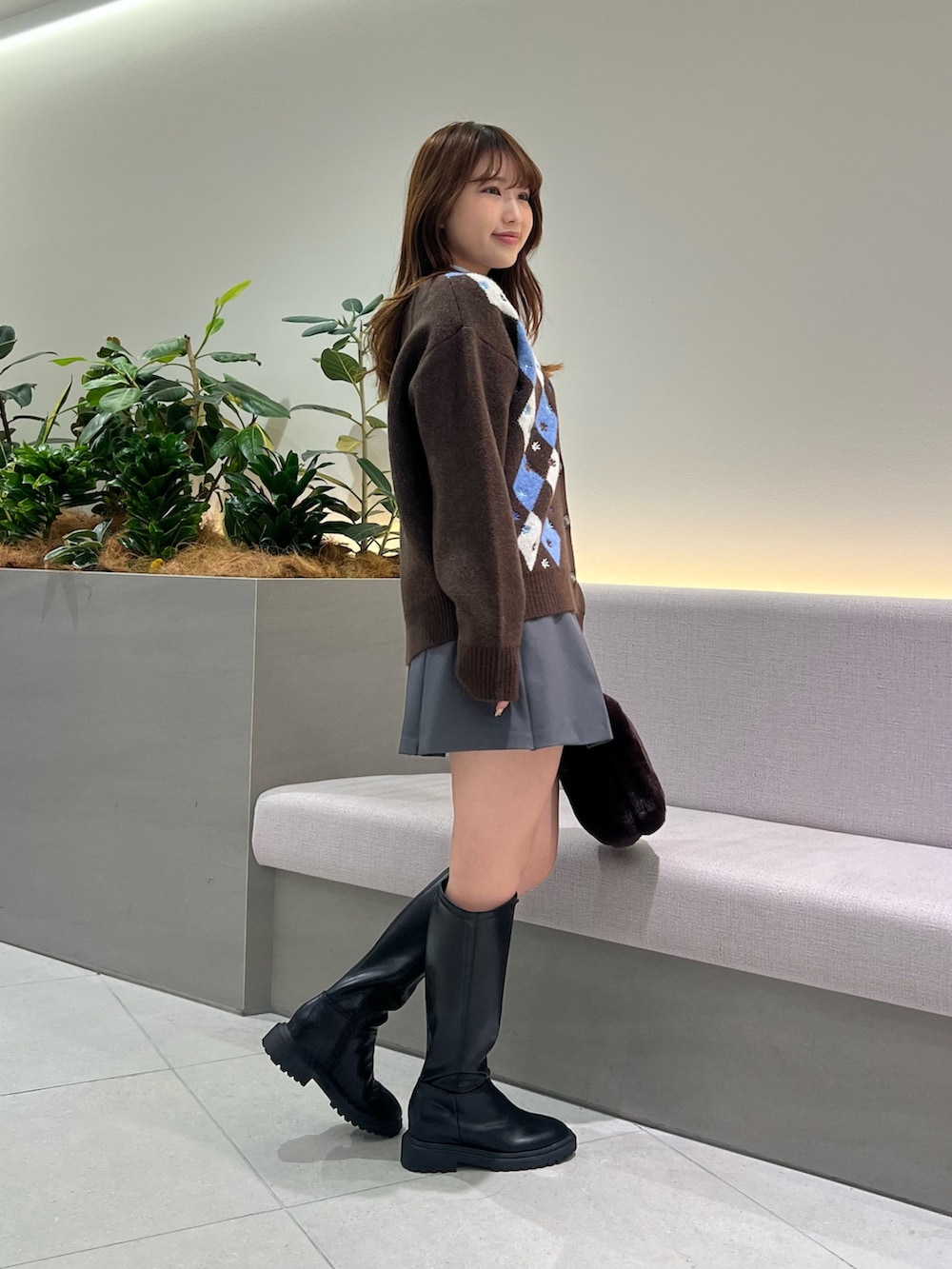 ブラウン系のカーディガン/ボレロ、ブルー系のTシャツ/カットソー、グレー系のスカートを着用したレディースの秋コーディネートの5枚目の写真