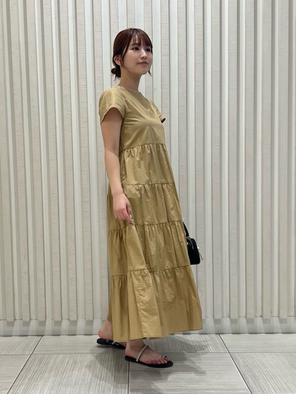 ベージュ系のワンピース、ブラウン系のサンダル、ブラウン系のボストンバッグを着用したレディースの夏コーディネートの3枚目の写真