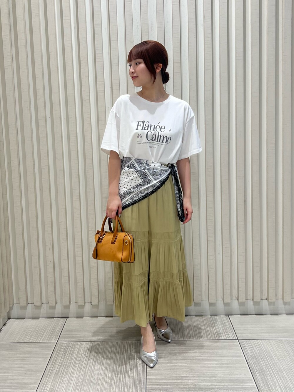 ホワイト系のTシャツ/カットソー、イエロー系のスカート、オレンジ系のボストンバッグを着用したレディースの夏コーディネートの2枚目の写真