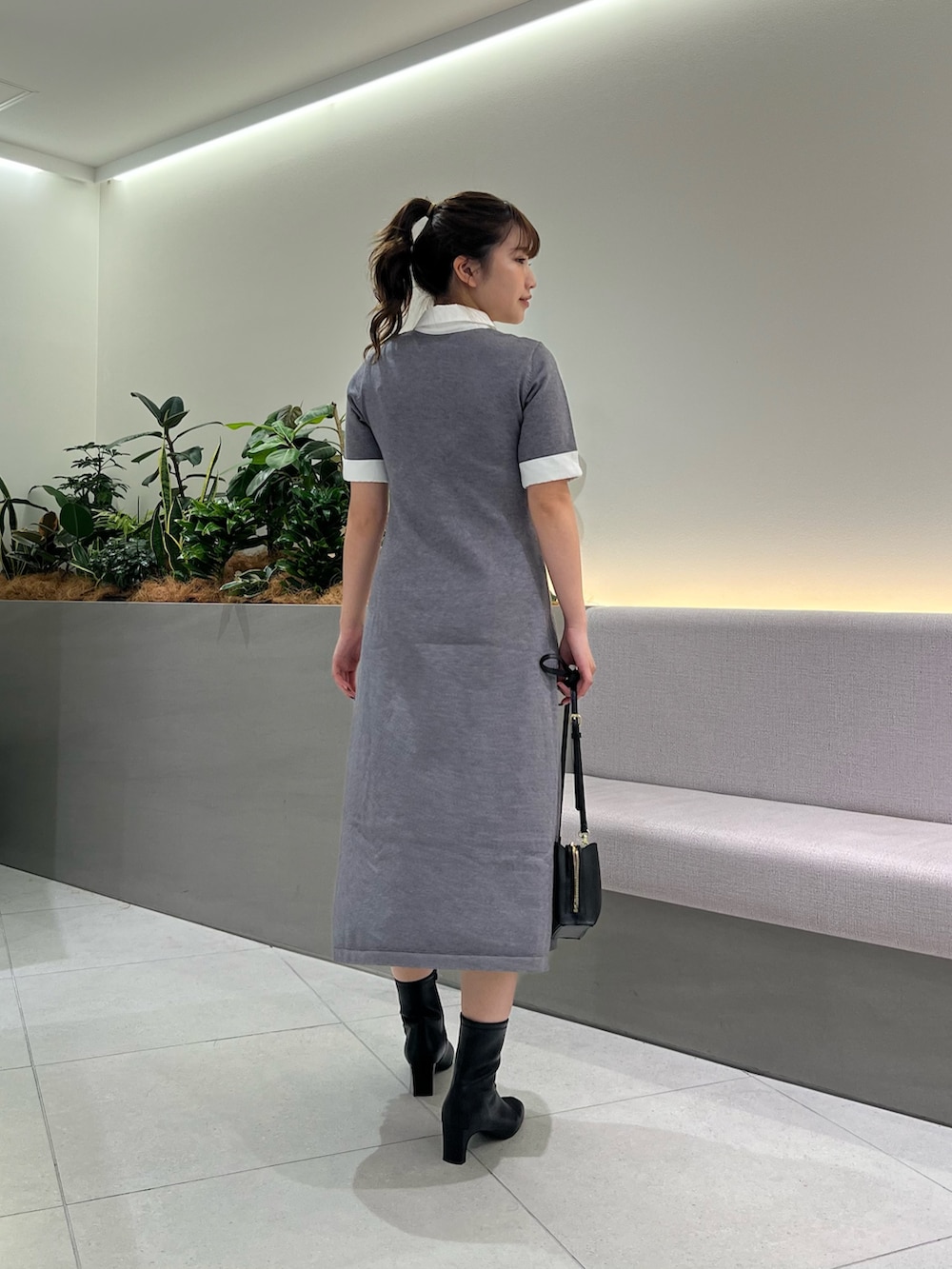 グレー系のワンピース、ブラック系のブーツ、ブラック系のショルダーバッグを着用したレディースの秋コーディネートの7枚目の写真