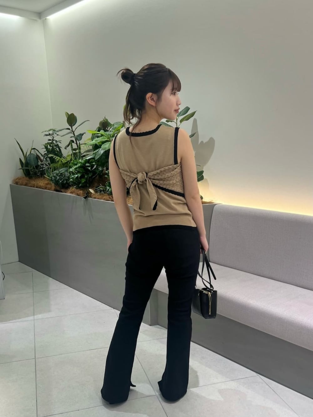 ベージュ系のニット/セーター、ブラック系のデニムパンツ、ブラック系のショルダーバッグを着用したレディースの夏コーディネートの6枚目の写真