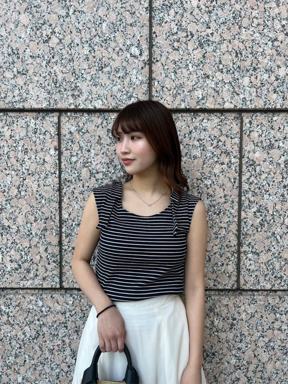 ホワイト系のスカート、ブルー系のTシャツ/カットソー、ベージュ系のトートバッグを着用したレディースの夏コーディネートの4枚目の写真