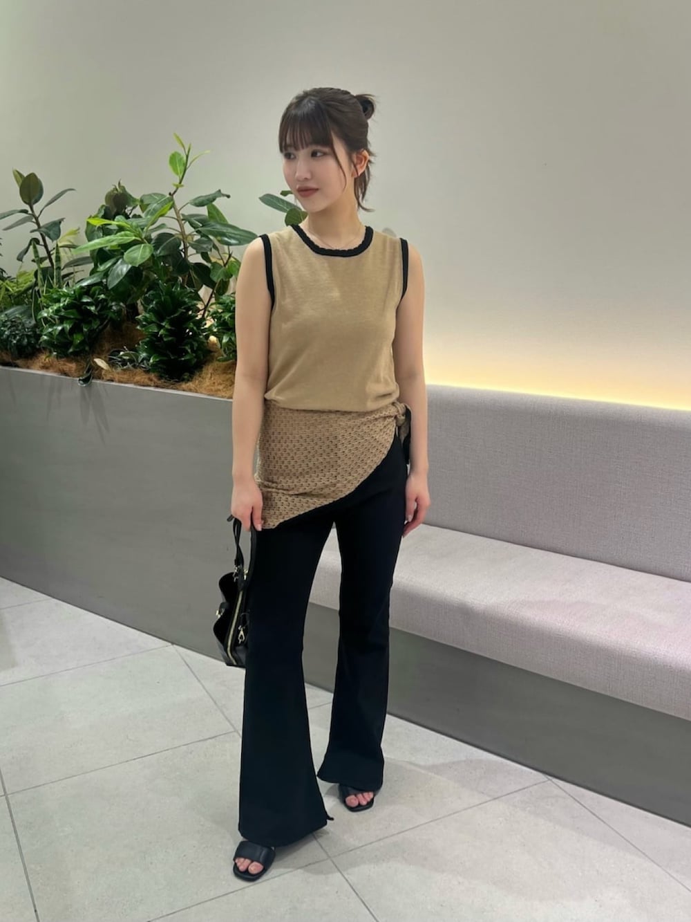 ベージュ系のニット/セーター、ブラック系のデニムパンツ、ブラック系のショルダーバッグを着用したレディースの夏コーディネートの4枚目の写真