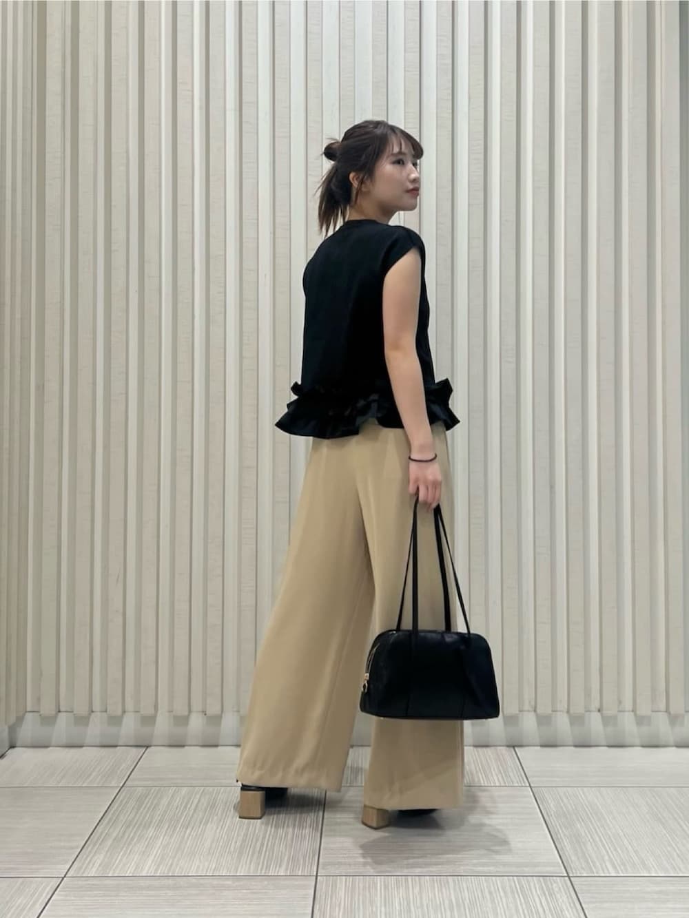 ブラック系のベスト、イエロー系のその他パンツ、ブラウン系のボストンバッグを着用したレディースの夏コーディネートの4枚目の写真