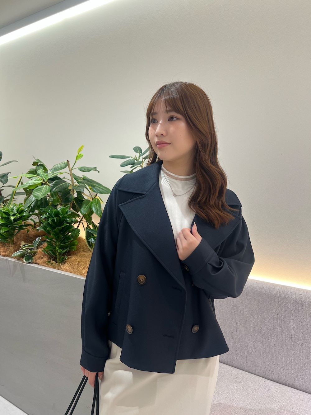 ブルー系のトレンチコート、ホワイト系のニット/セーター、ホワイト系のスカートを着用したレディースの秋コーディネートの7枚目の写真
