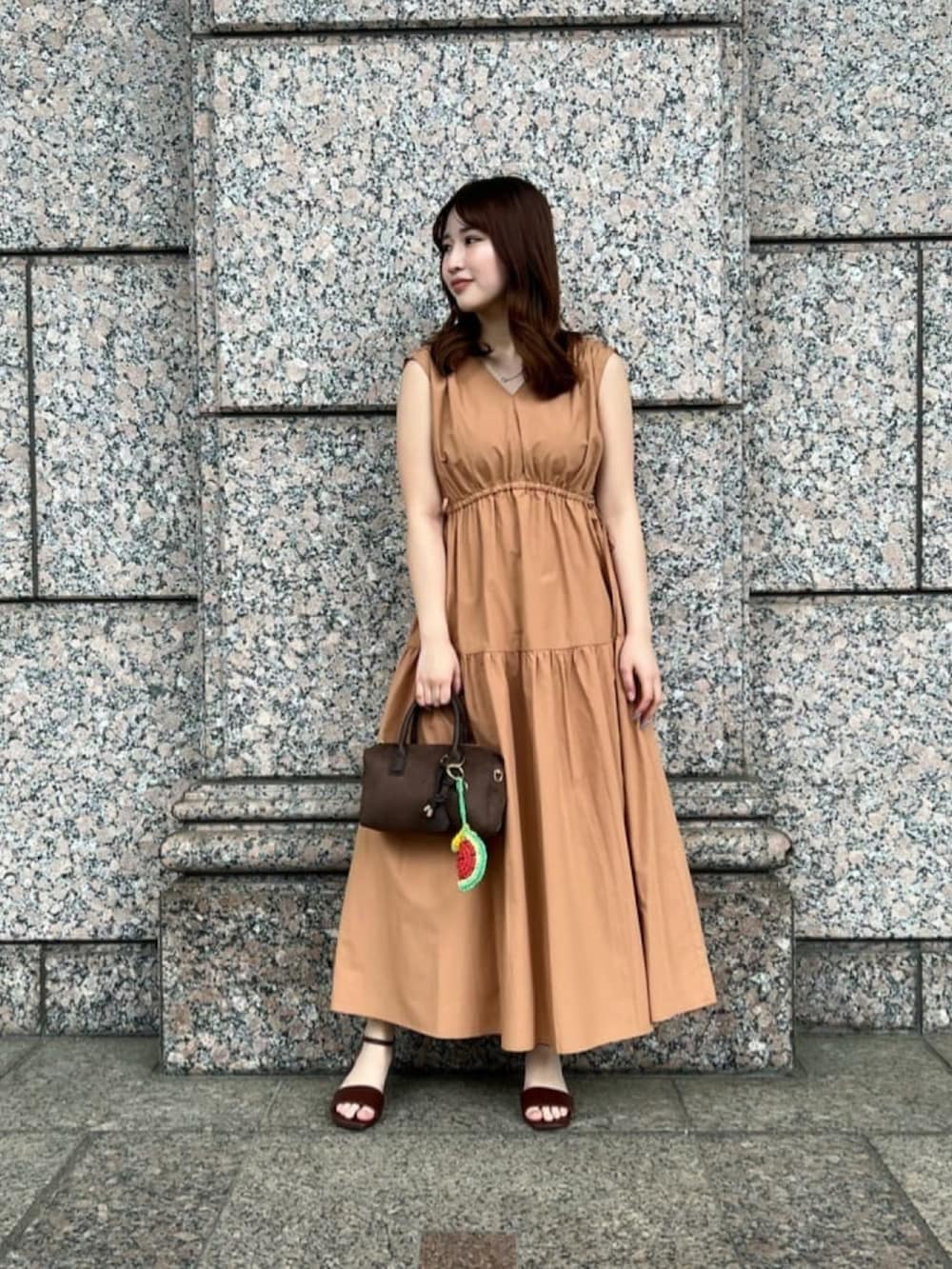 イエロー系のワンピース、ブラウン系のサンダル、ブラウン系のボストンバッグを着用したレディースの夏コーディネートの2枚目の写真