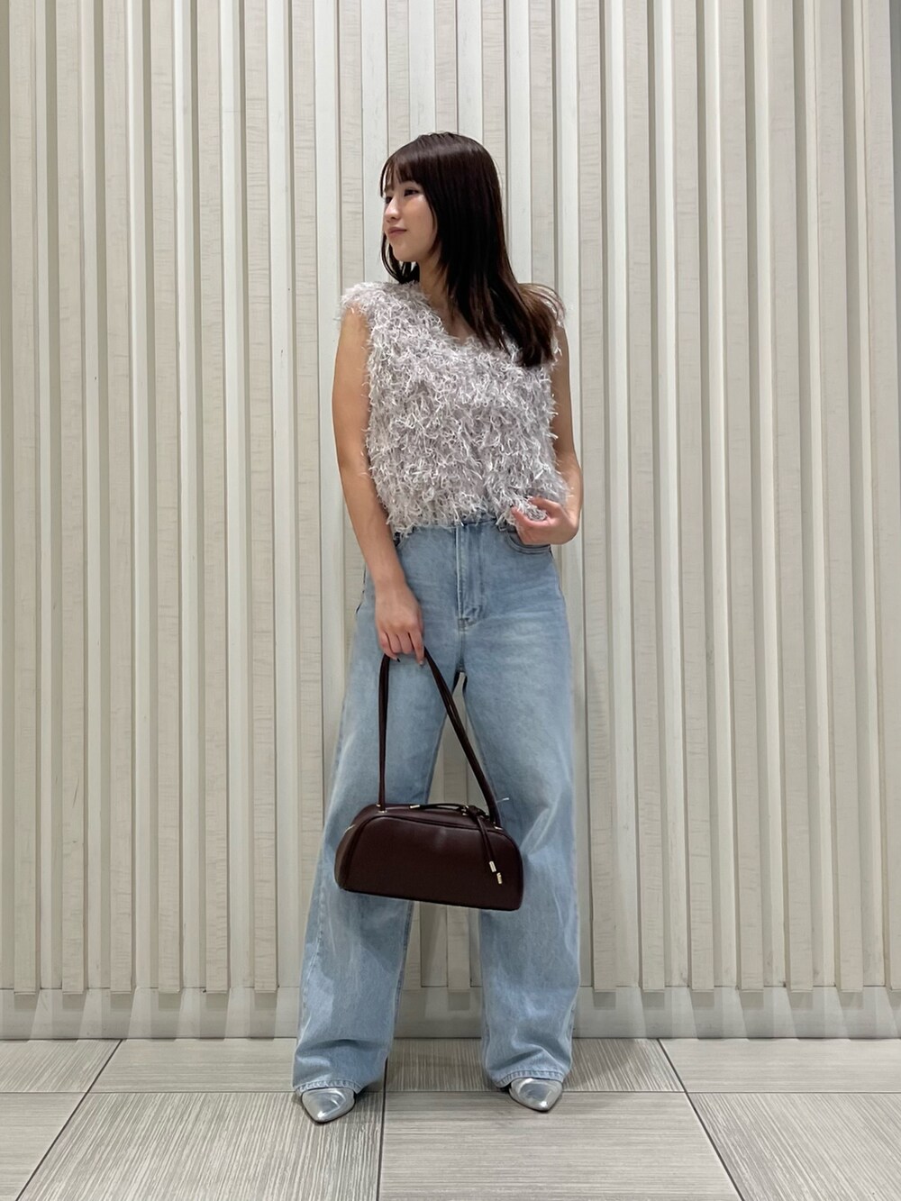 グレー系のベスト、ブルー系のデニムパンツ、ブラウン系のボストンバッグを着用したレディースの夏コーディネートの3枚目の写真