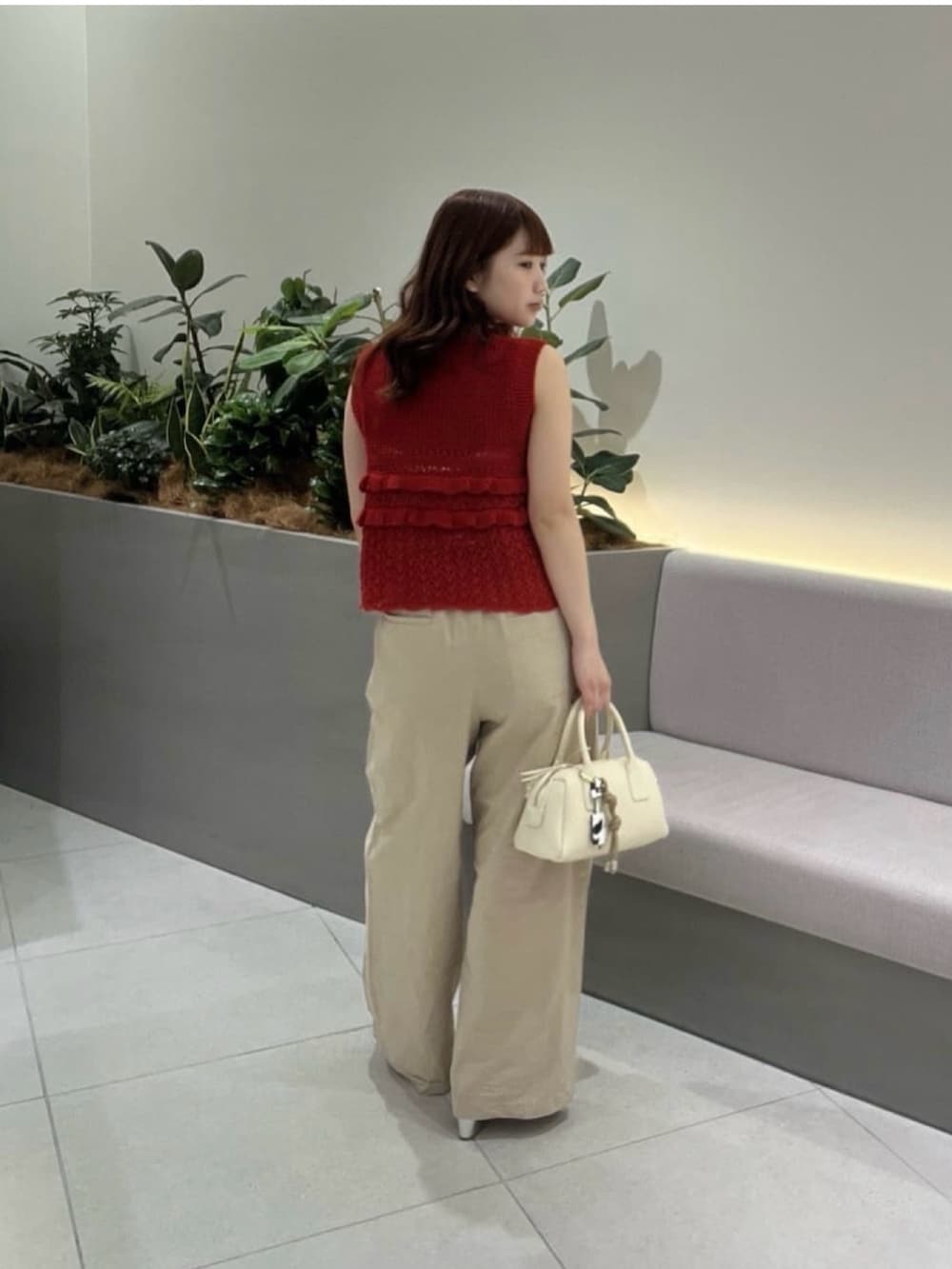 レッド系のニット/セーター、ベージュ系のその他パンツ、ブラウン系のボストンバッグを着用したレディースの夏コーディネートの4枚目の写真