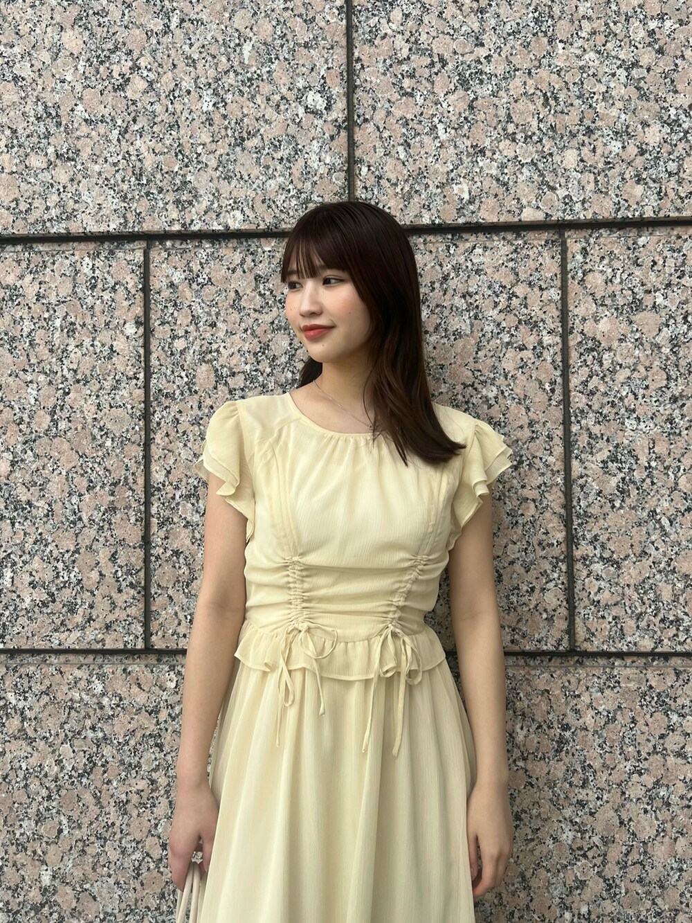 イエロー系のワンピース、ホワイト系のボストンバッグ、ホワイト系のサンダルを着用したレディースの夏コーディネートの5枚目の写真
