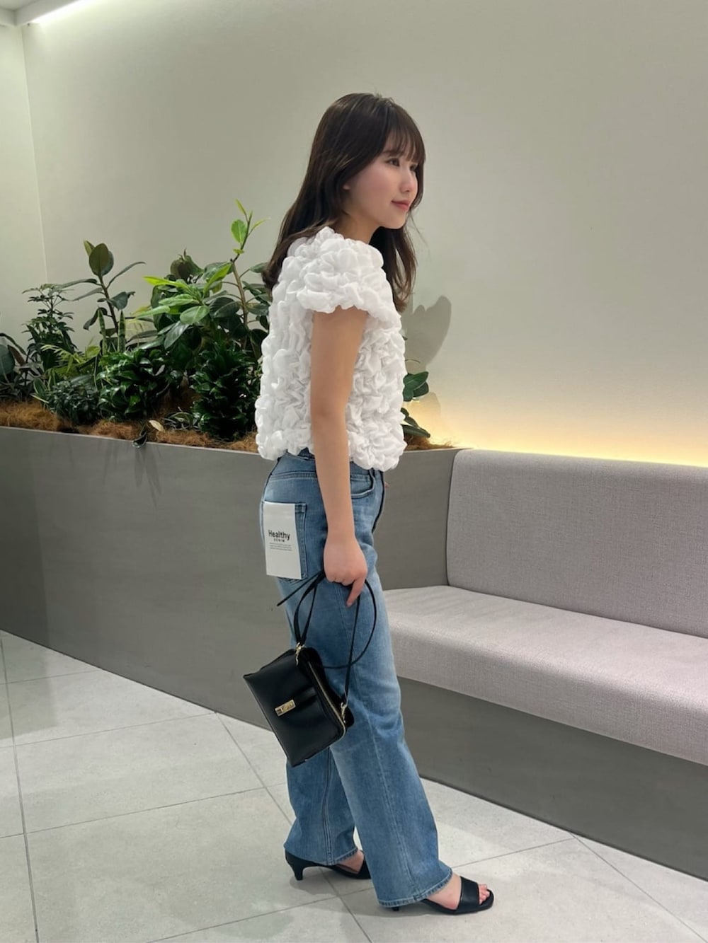 ブルー系のデニムパンツ、ホワイト系のシャツ/ブラウス、ブラック系のショルダーバッグを着用したレディースの夏コーディネートの4枚目の写真