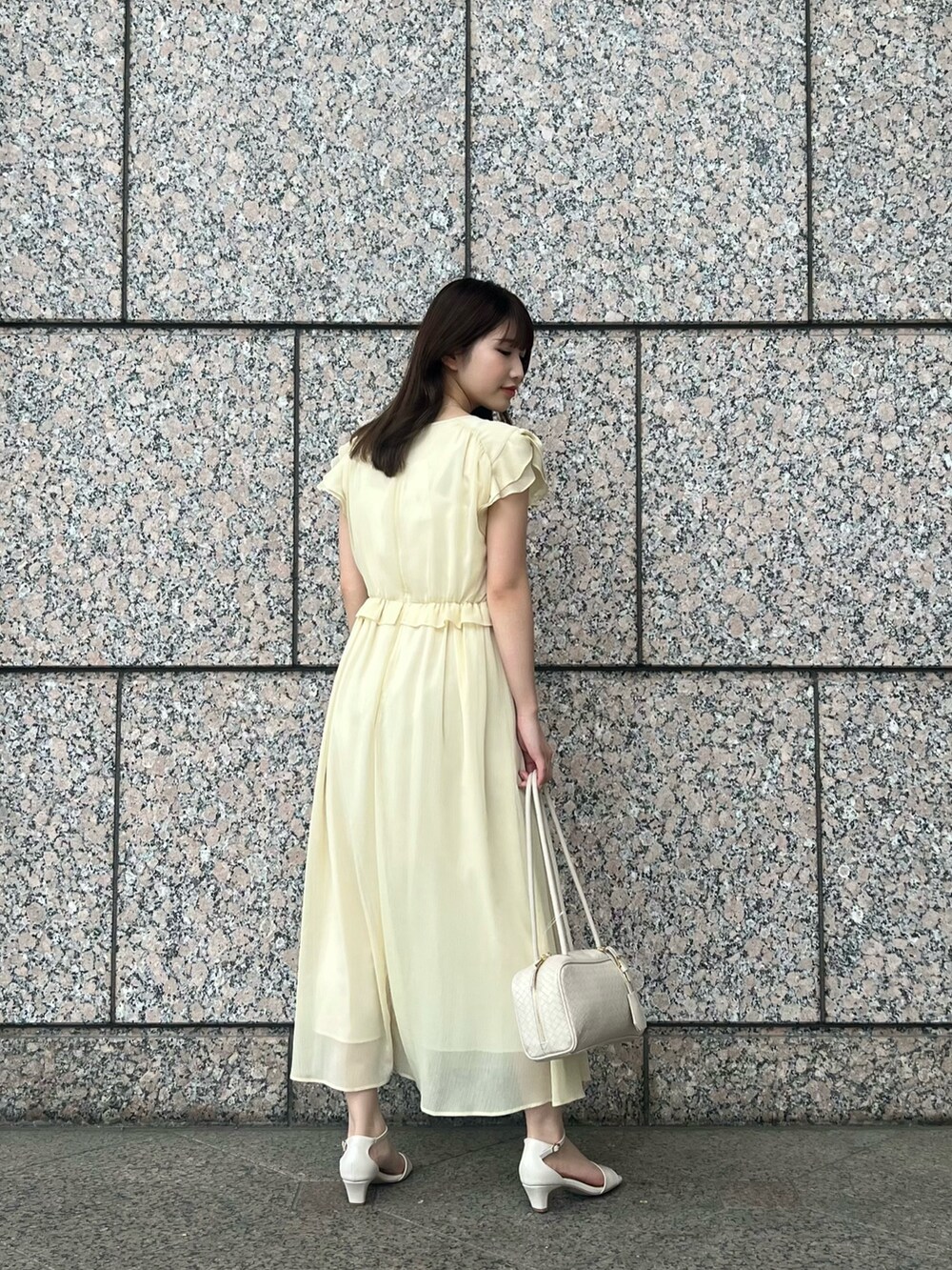 イエロー系のワンピース、ホワイト系のボストンバッグ、ホワイト系のサンダルを着用したレディースの夏コーディネートの4枚目の写真
