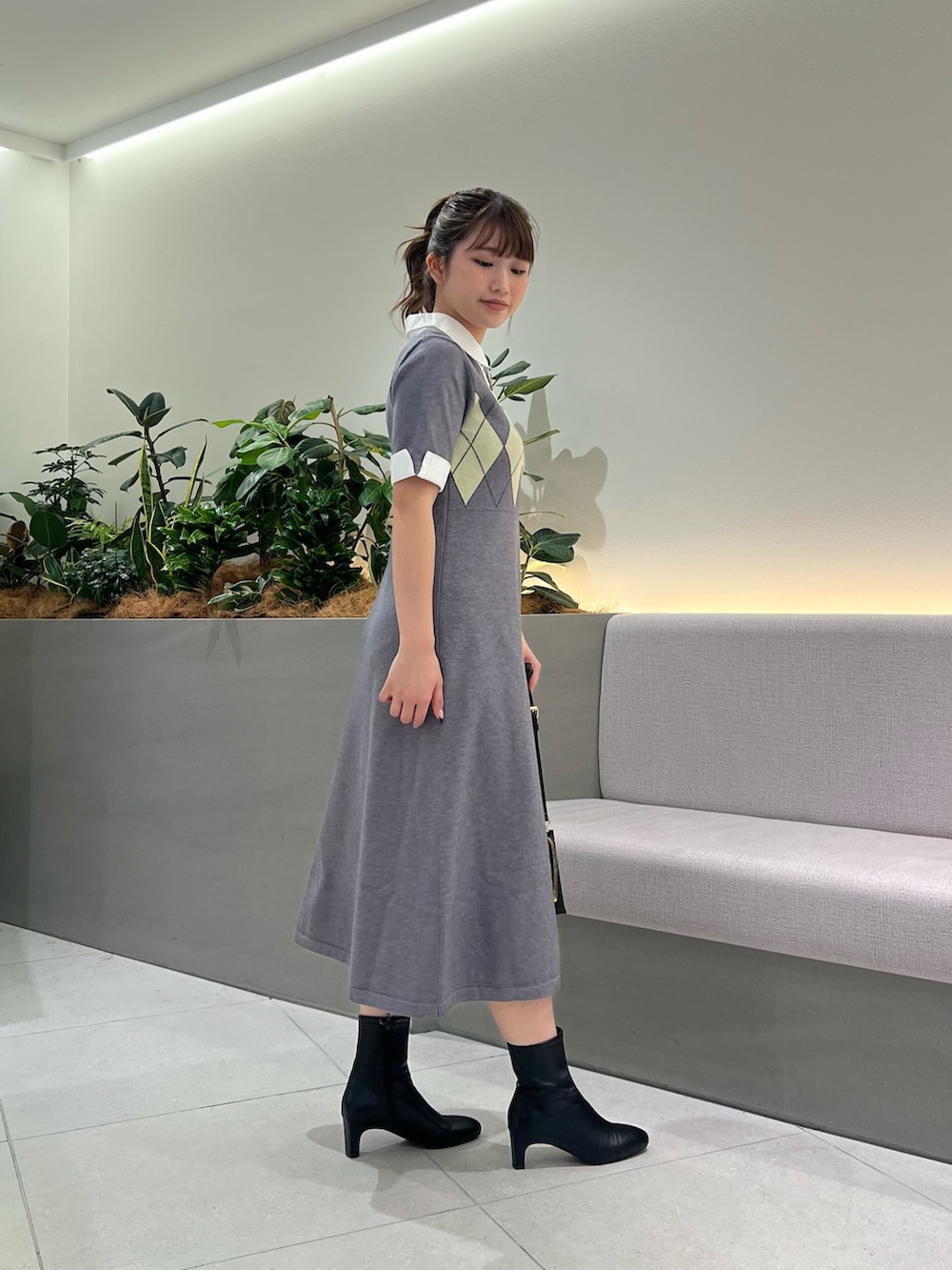 グレー系のワンピース、ブラック系のブーツ、ブラック系のショルダーバッグを着用したレディースの秋コーディネートの5枚目の写真