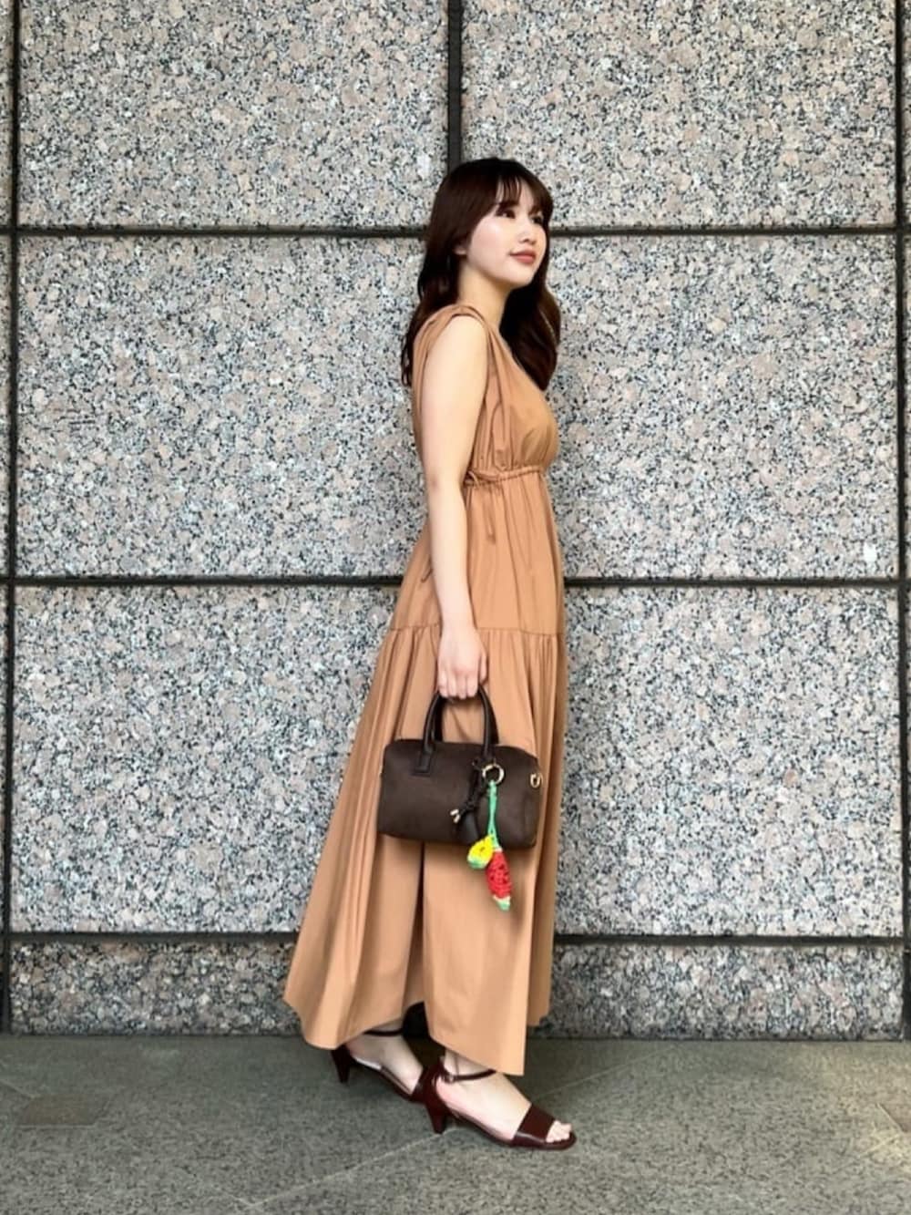 イエロー系のワンピース、ブラウン系のサンダル、ブラウン系のボストンバッグを着用したレディースの夏コーディネートの3枚目の写真