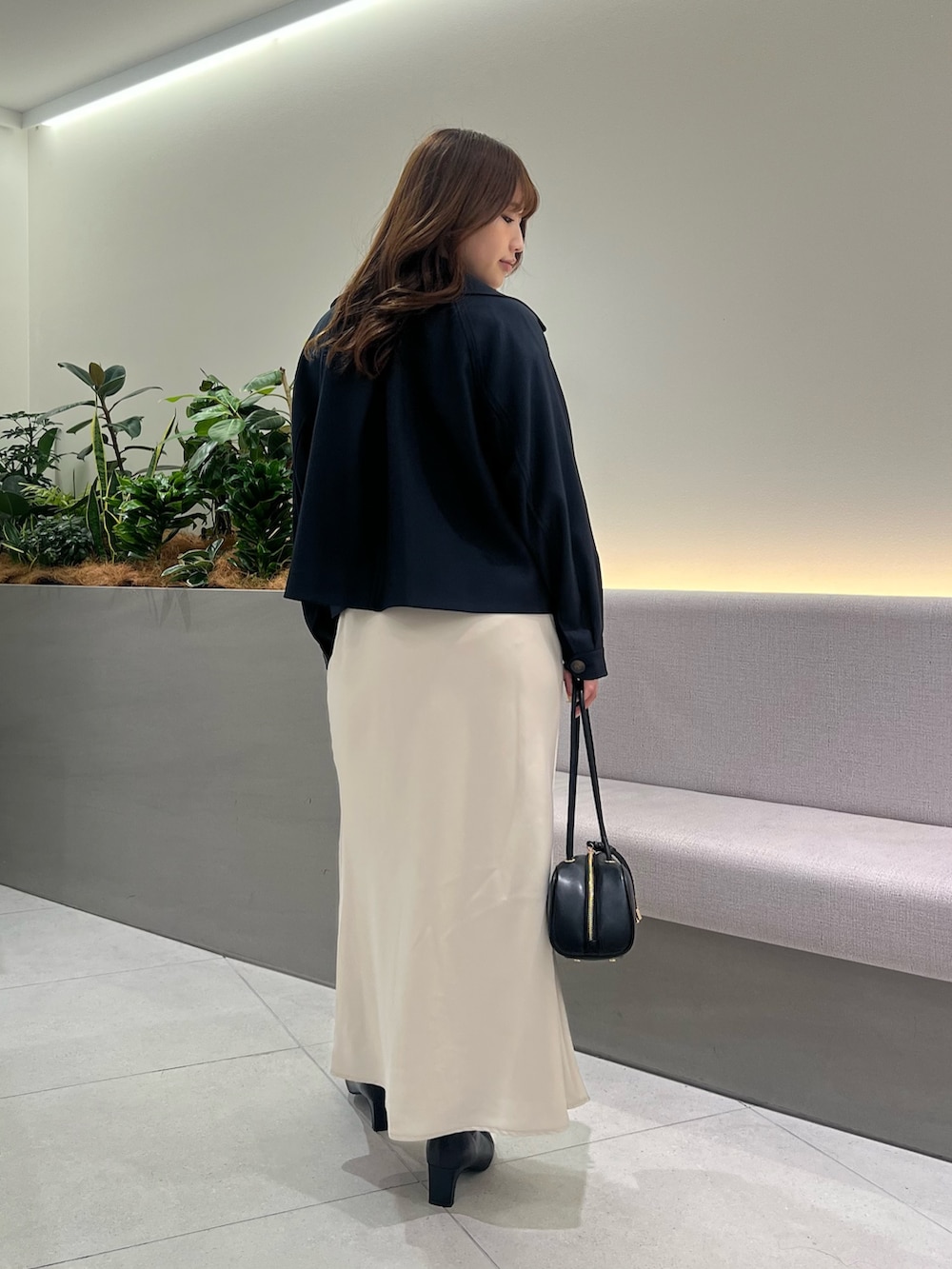 ブルー系のトレンチコート、ホワイト系のニット/セーター、ホワイト系のスカートを着用したレディースの秋コーディネートの6枚目の写真